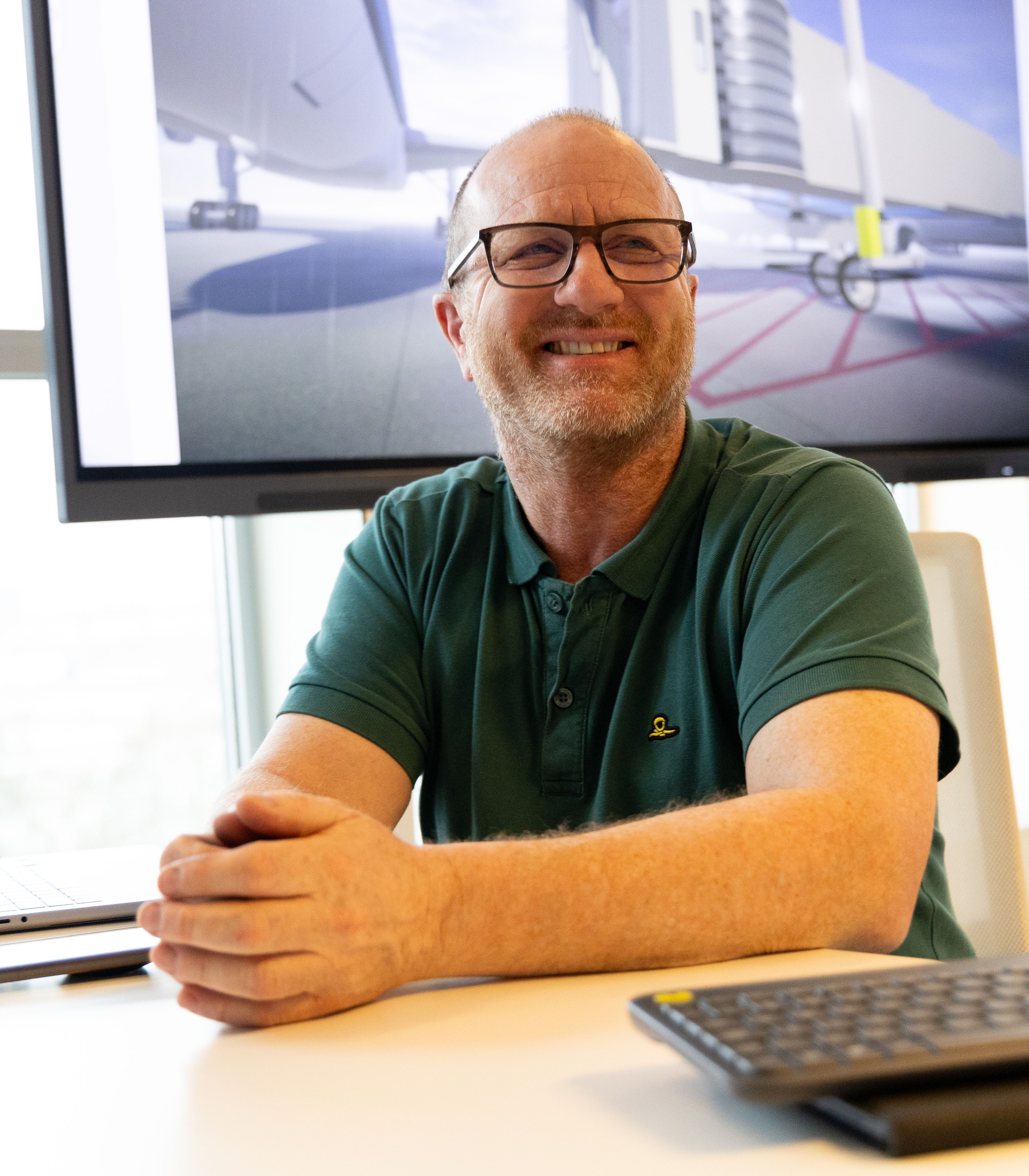 Man sitting behind a desk in front of a tv screen with a VR simulation