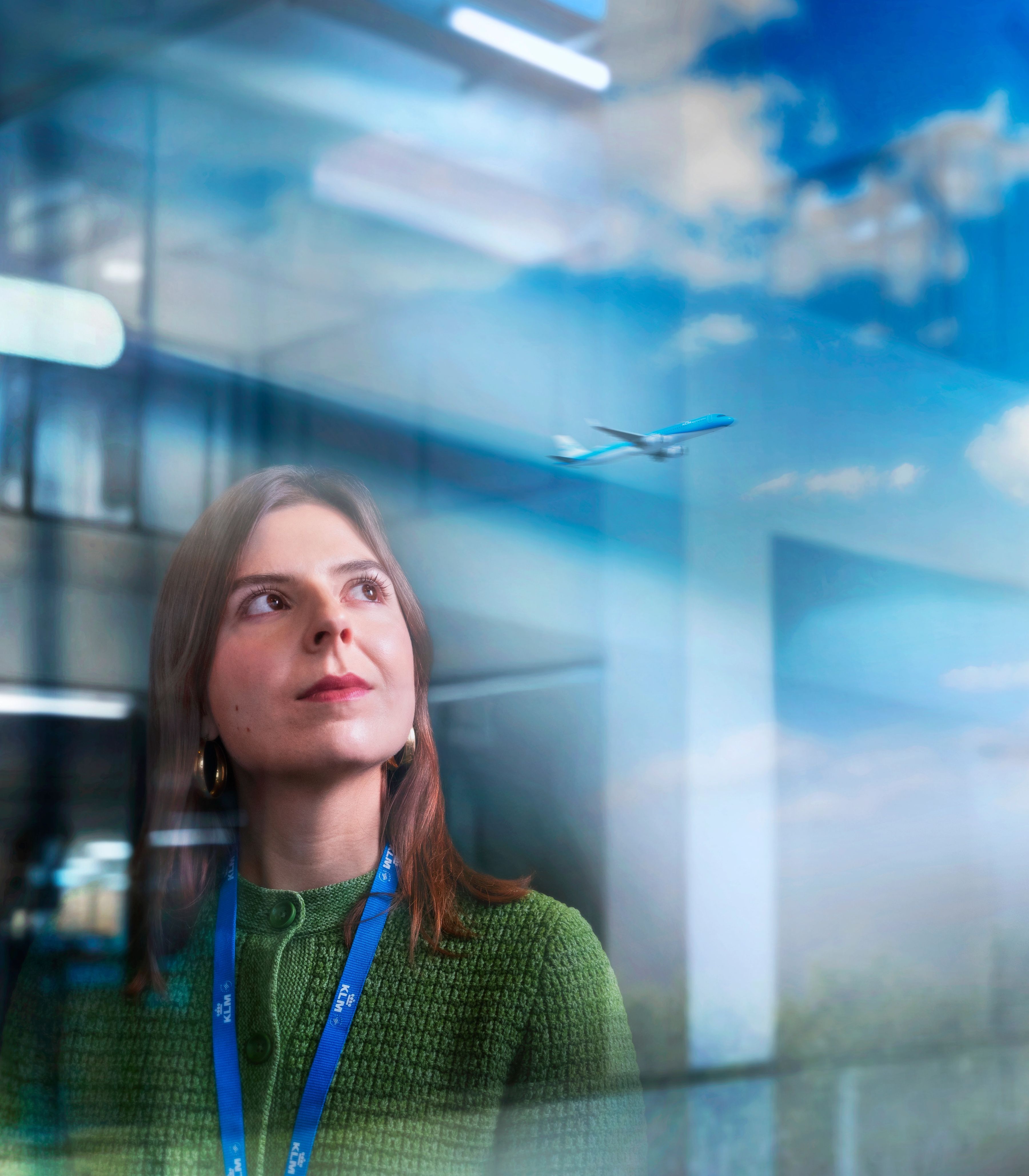 KLM office colleague standing in front of a line off trees with blue skies in the background.