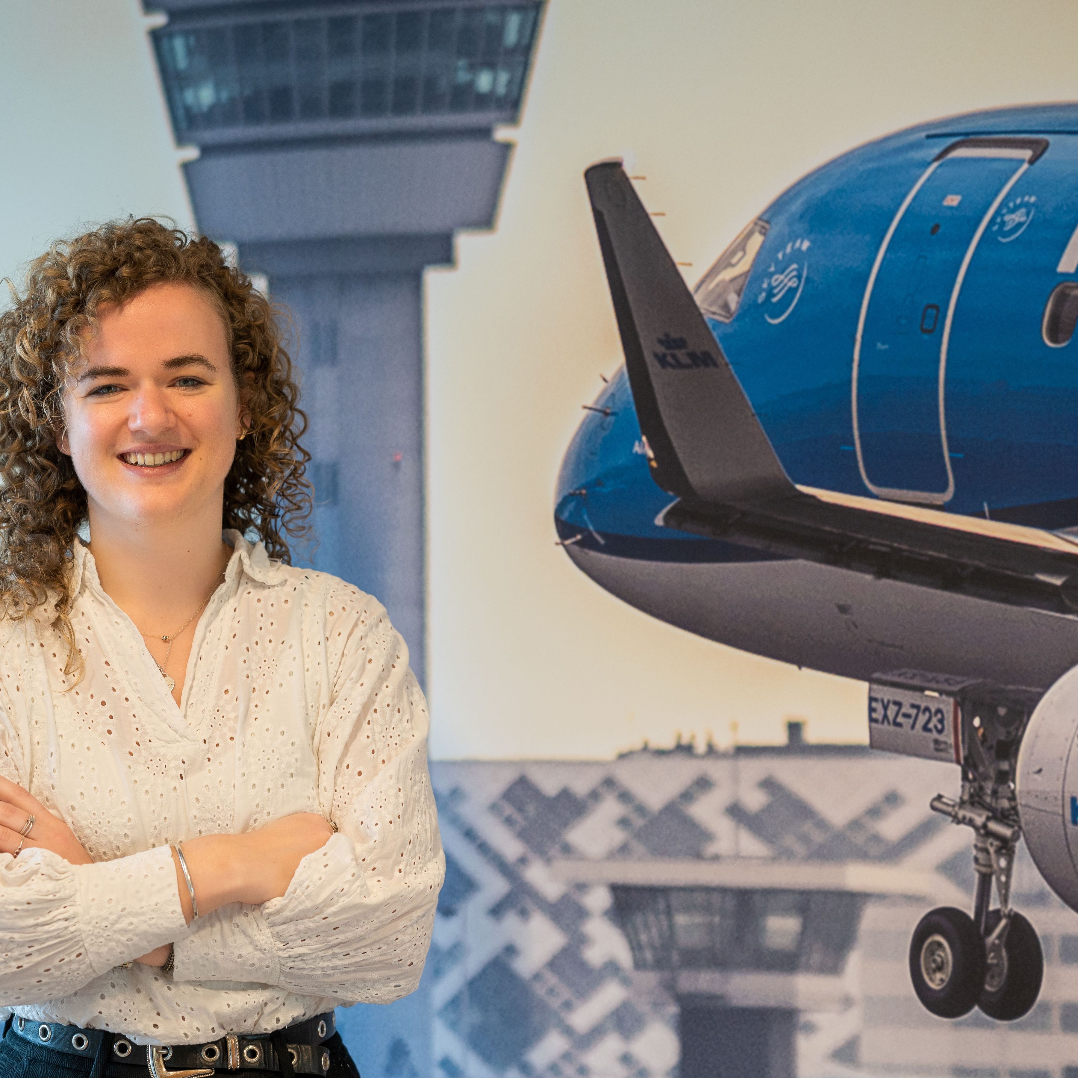 woman posing in front of an image of a landing plane