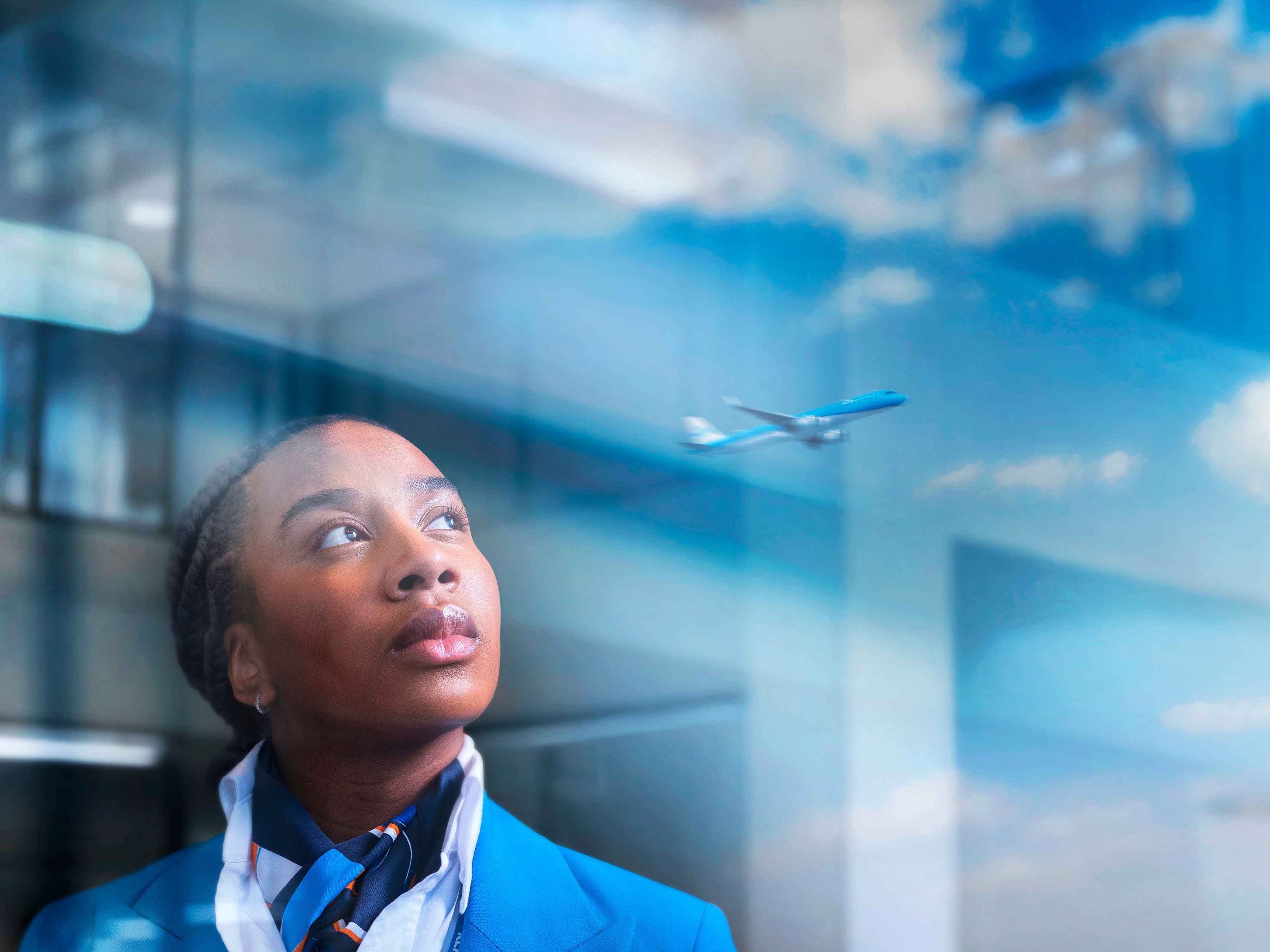 Service agent looking out of a big window in the reflection a departing plane