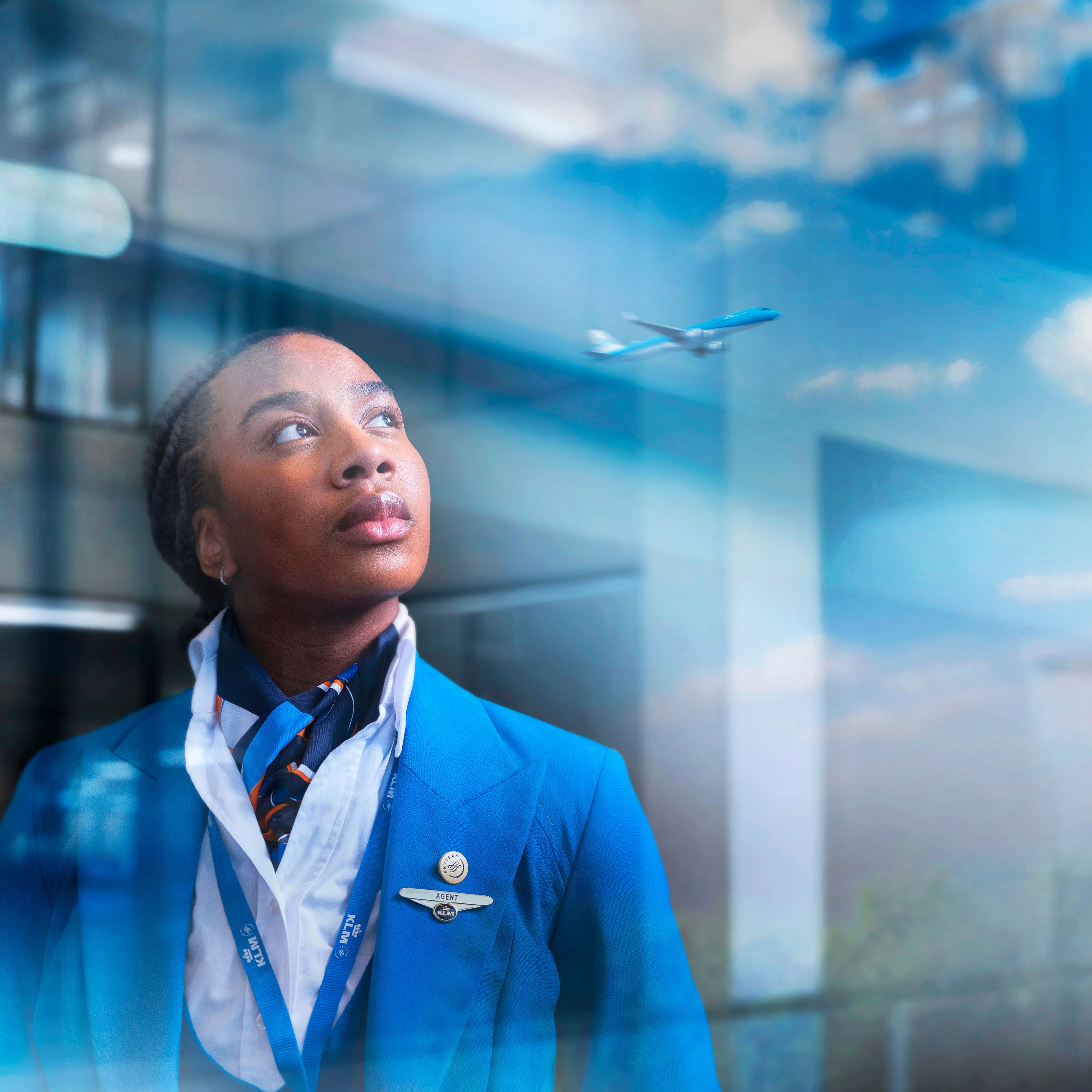 Service agent looking out of a big window in the reflection a departing plane