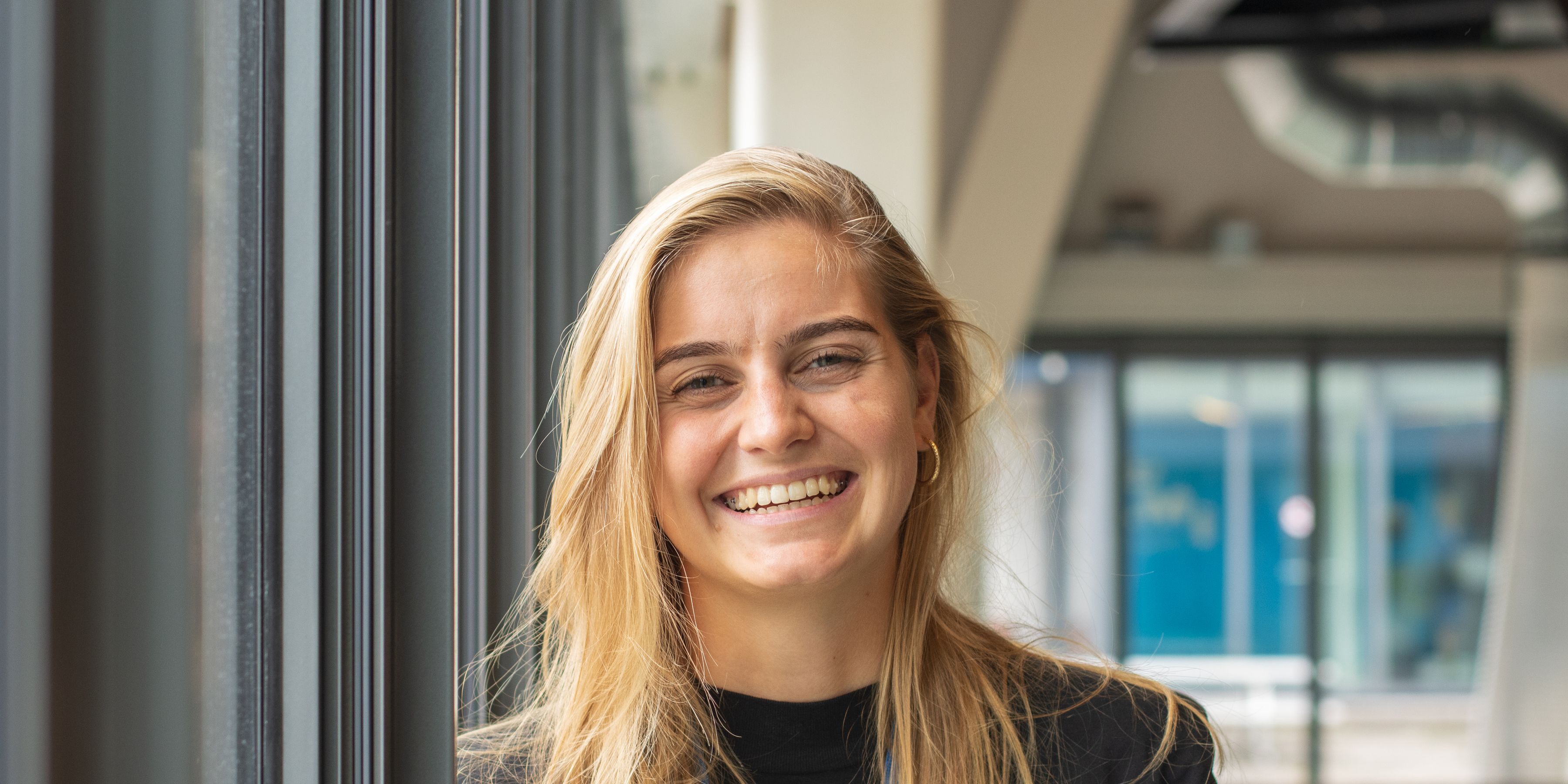 Een KLM medewerkster lacht naar de camera