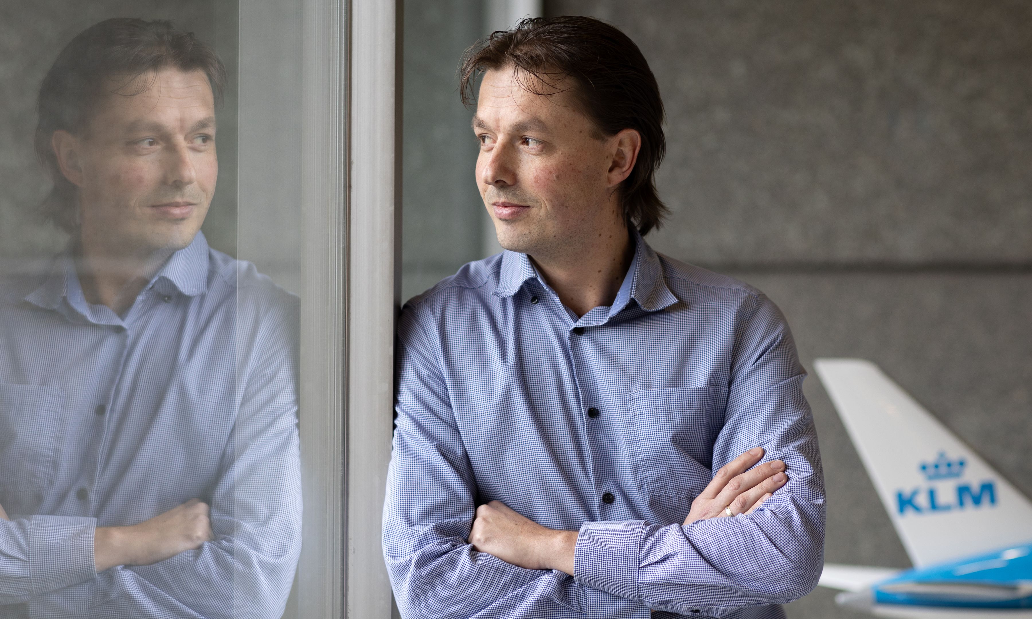 Man in het KLM-hoofdkantoor die naar zijn eigen reflectie kijkt