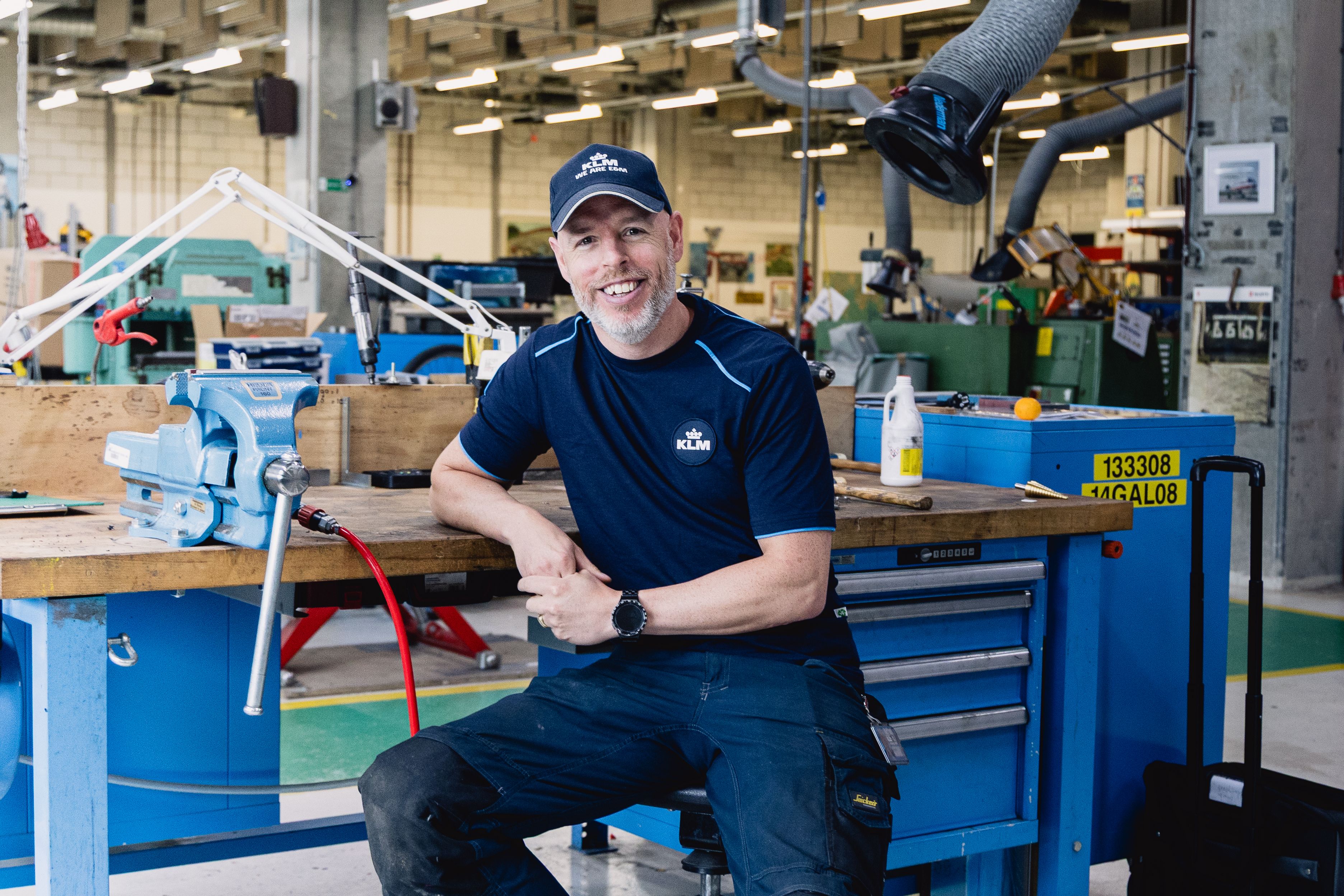 KLM employee sitting at his work desk in the maintenance workshop