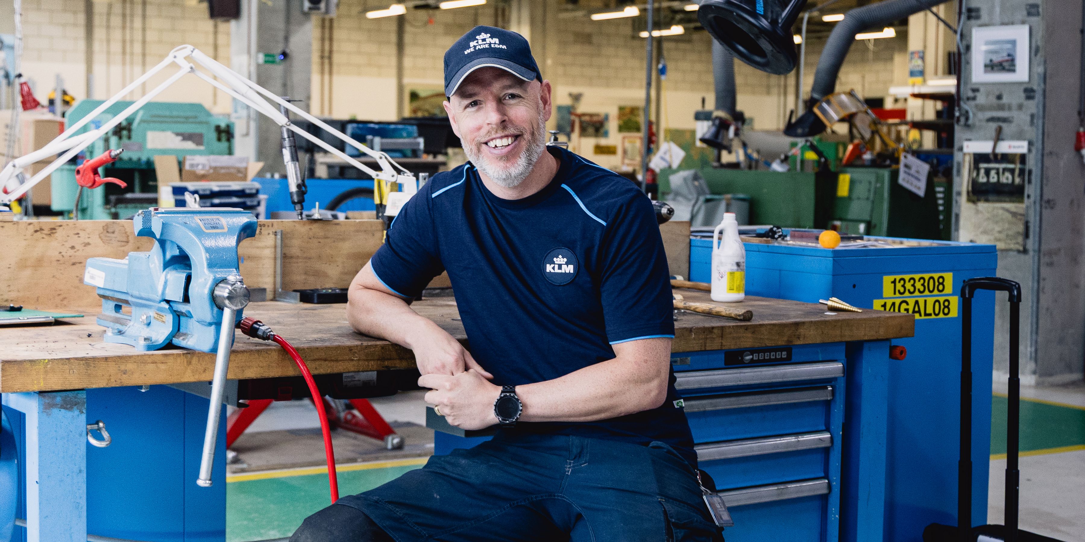 KLM employee sitting at his work desk in the maintenance workshop