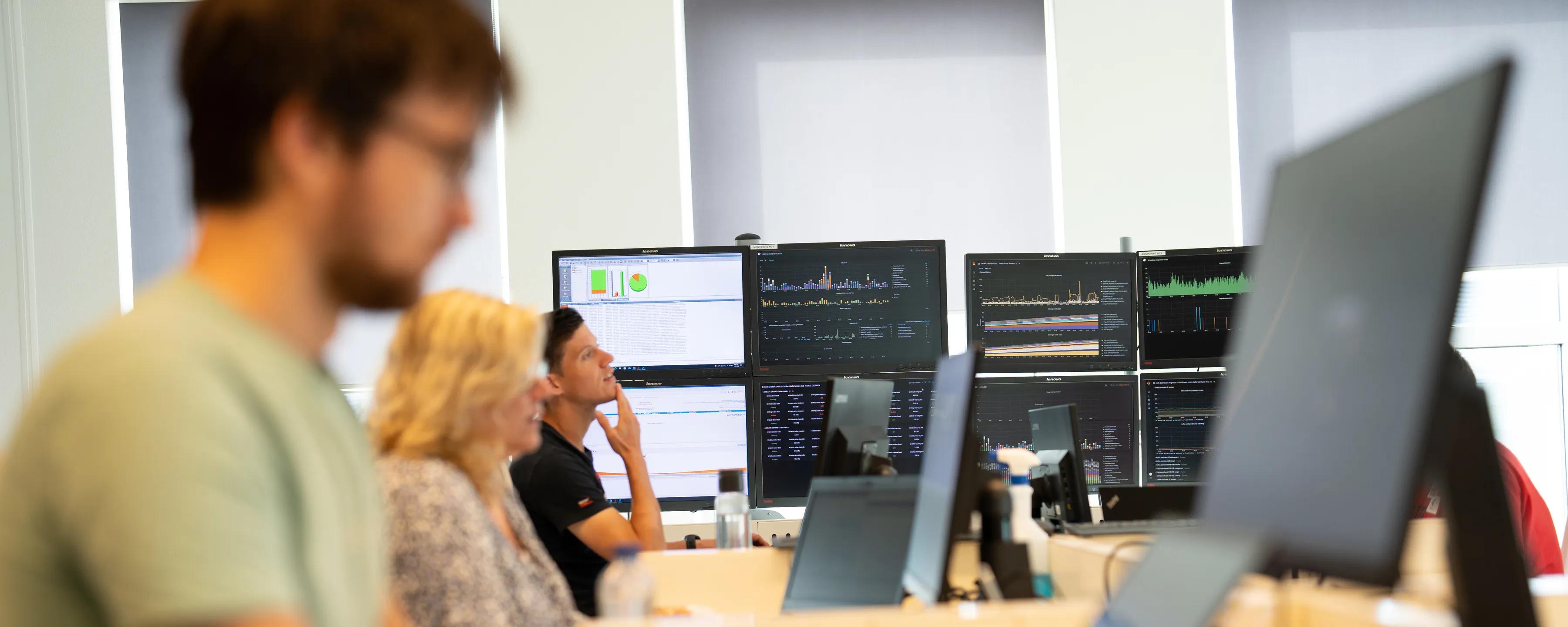 Mensen achter meerdere pc schermen