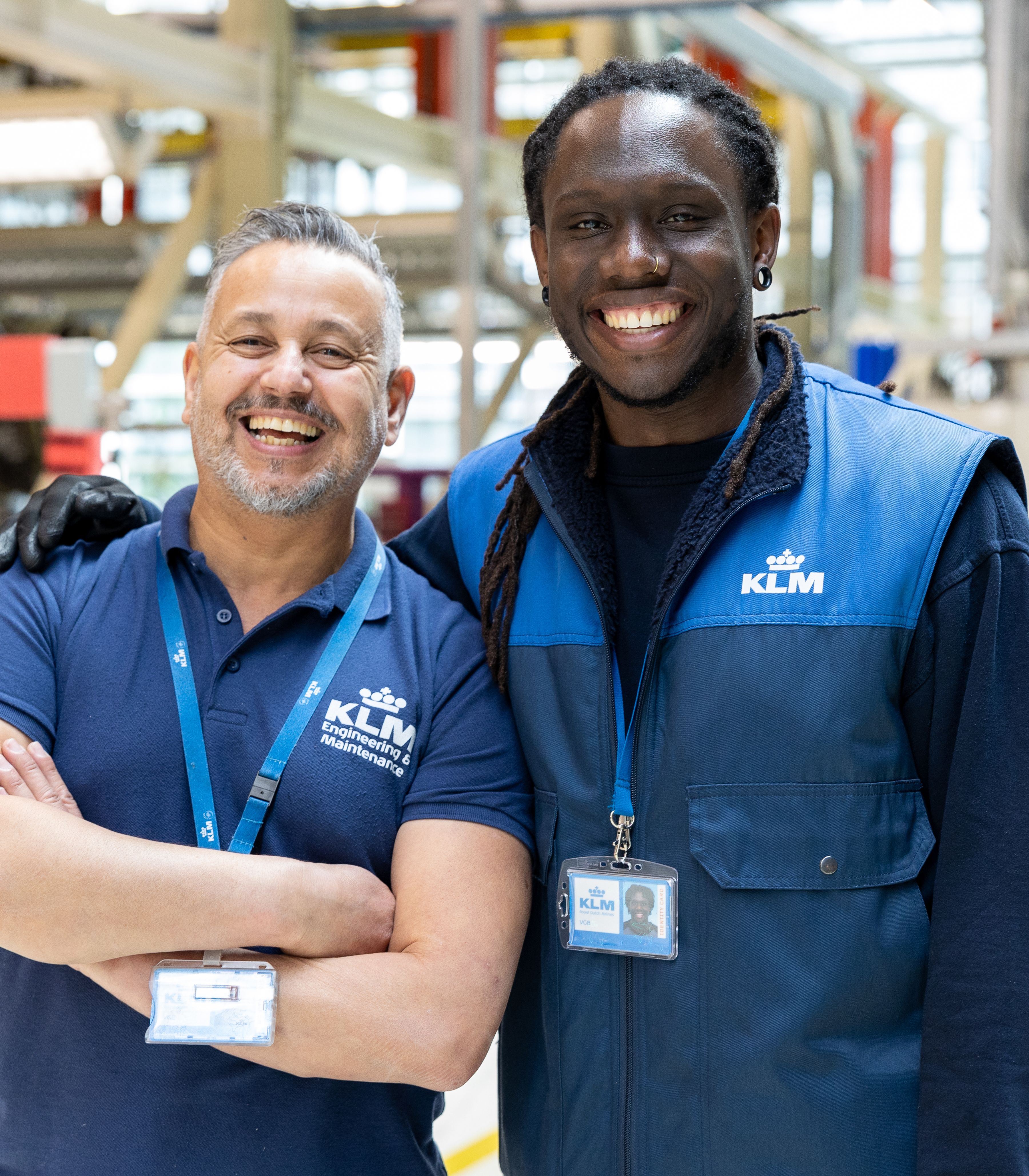 Twee lachende KLM-technicien die samen in een onderhoudshangar staan