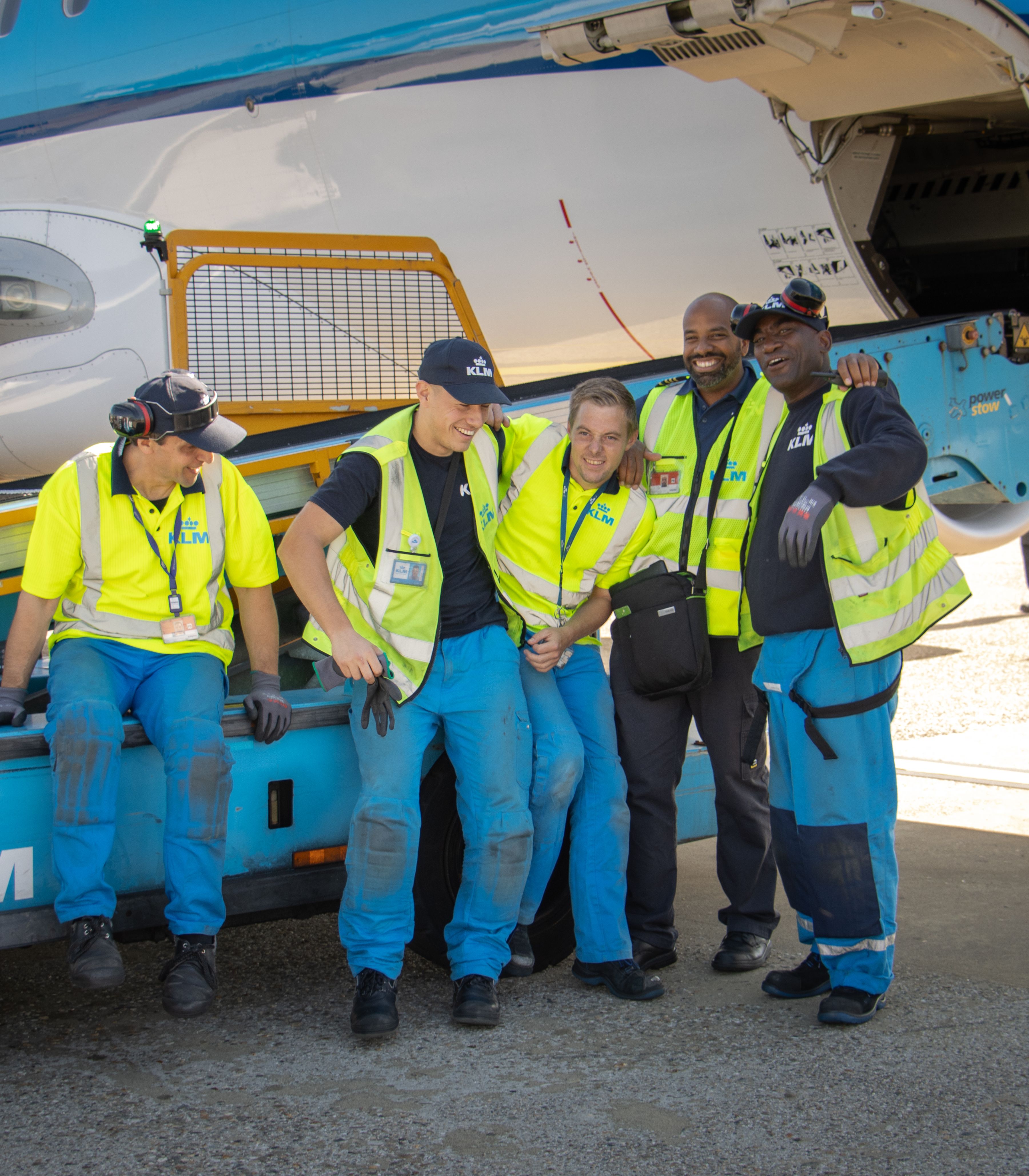 Ground operations team standing together in high-visibility clothing next to a KLM aircraft on the tarmac