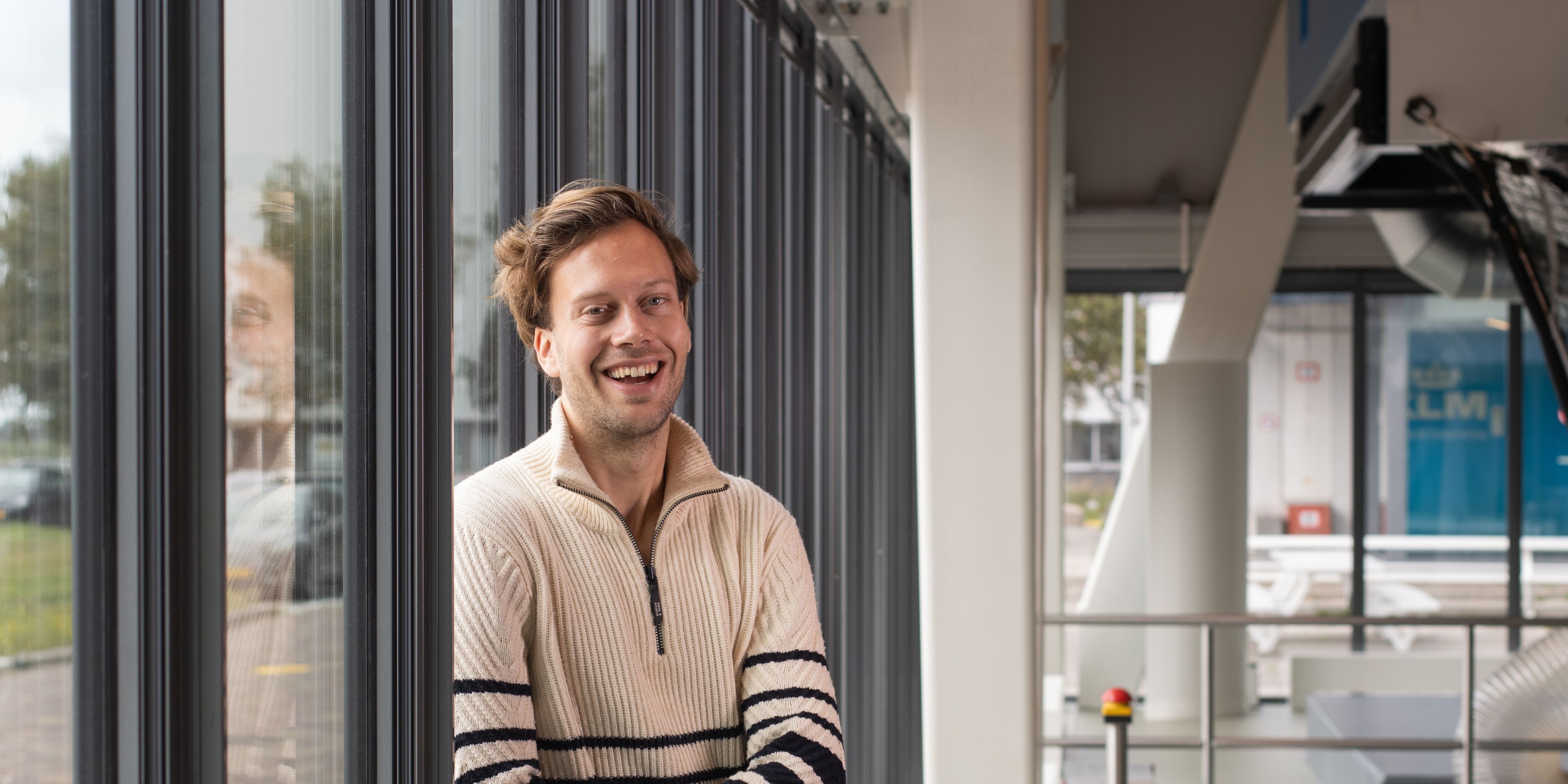 Een KLM medewerkter lacht naar de camera