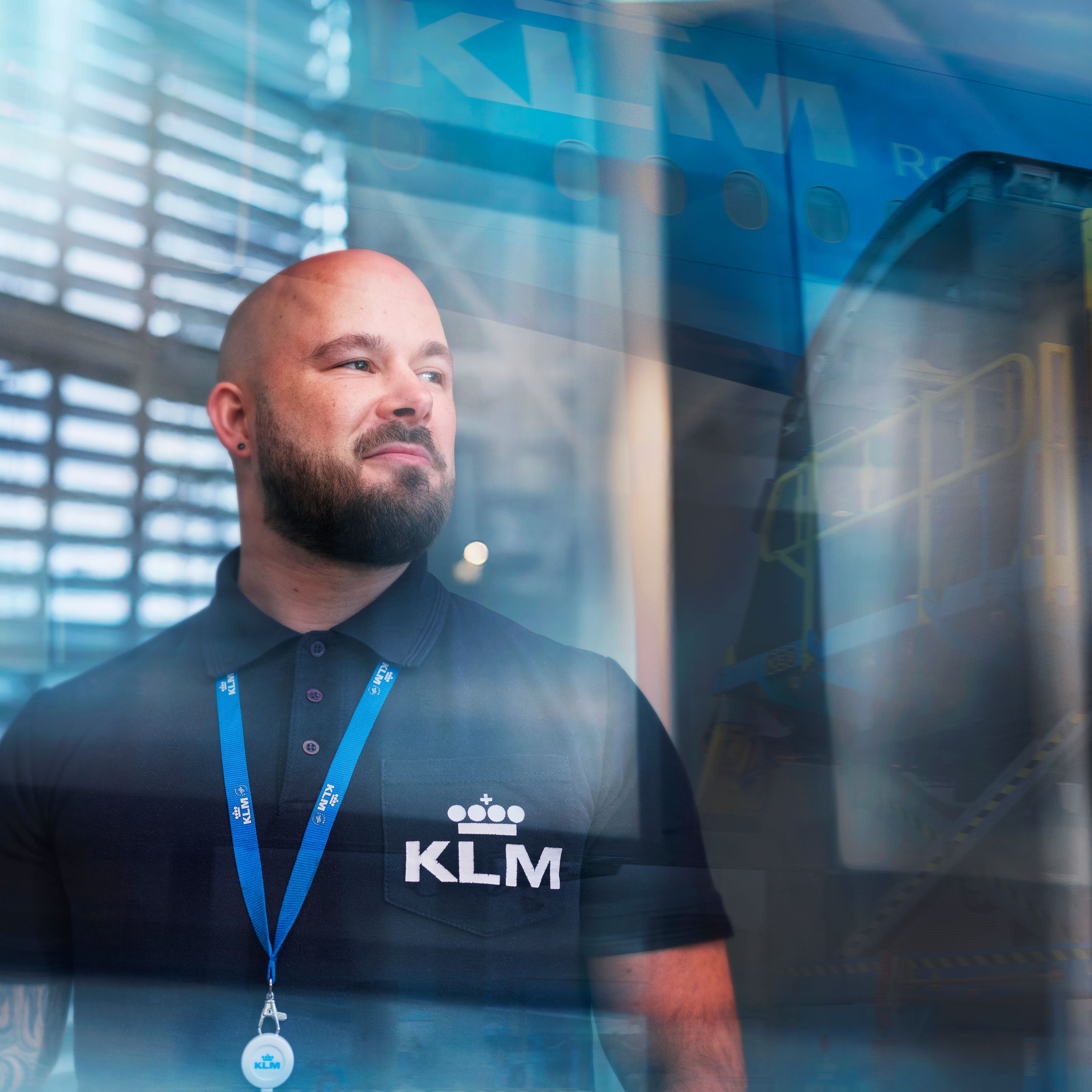 A male KLM ground services colleague is looking out of a large office window.