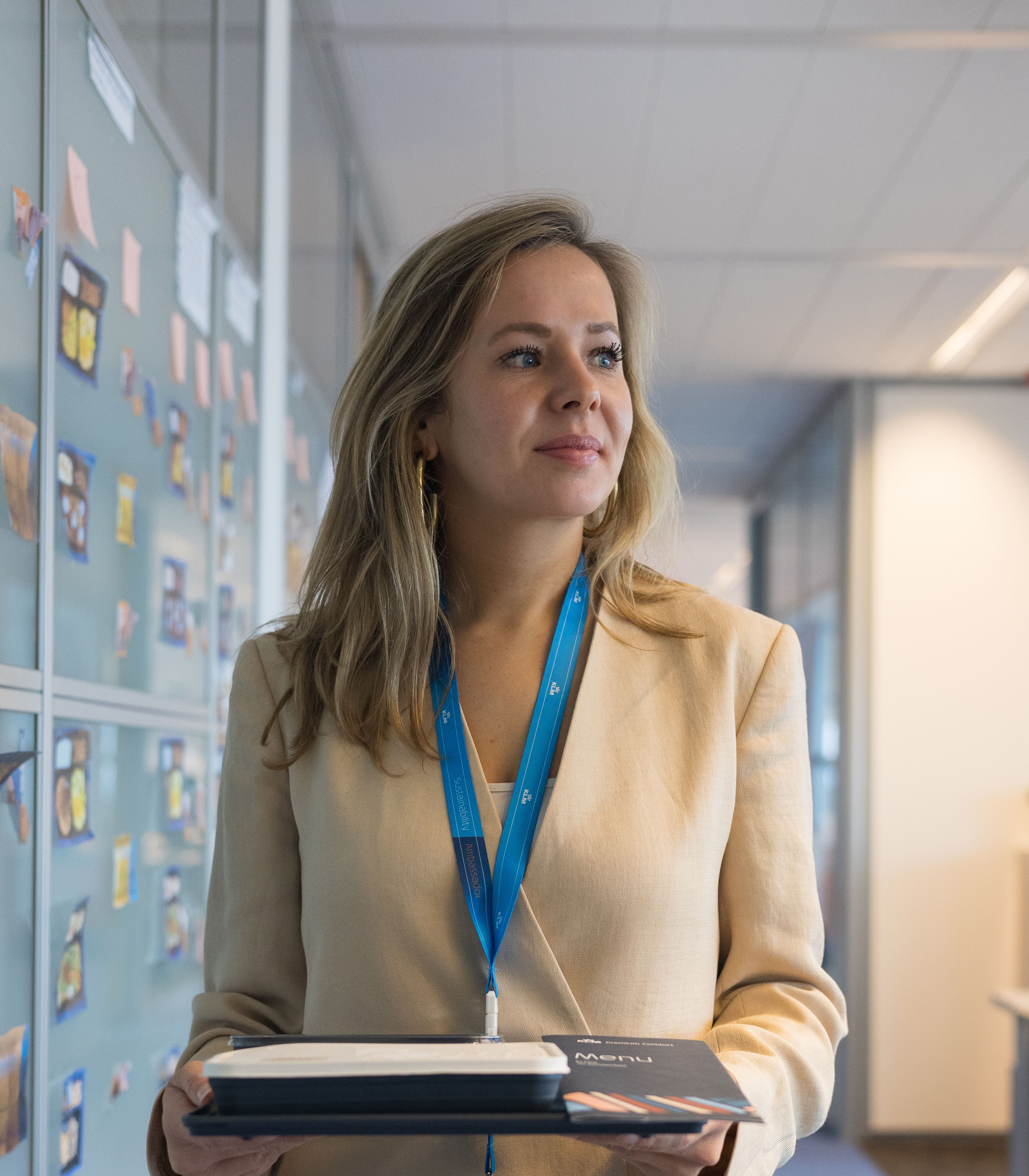 KLM colleague walking through a hallway holding a tray, wearing a badge and lanyard.