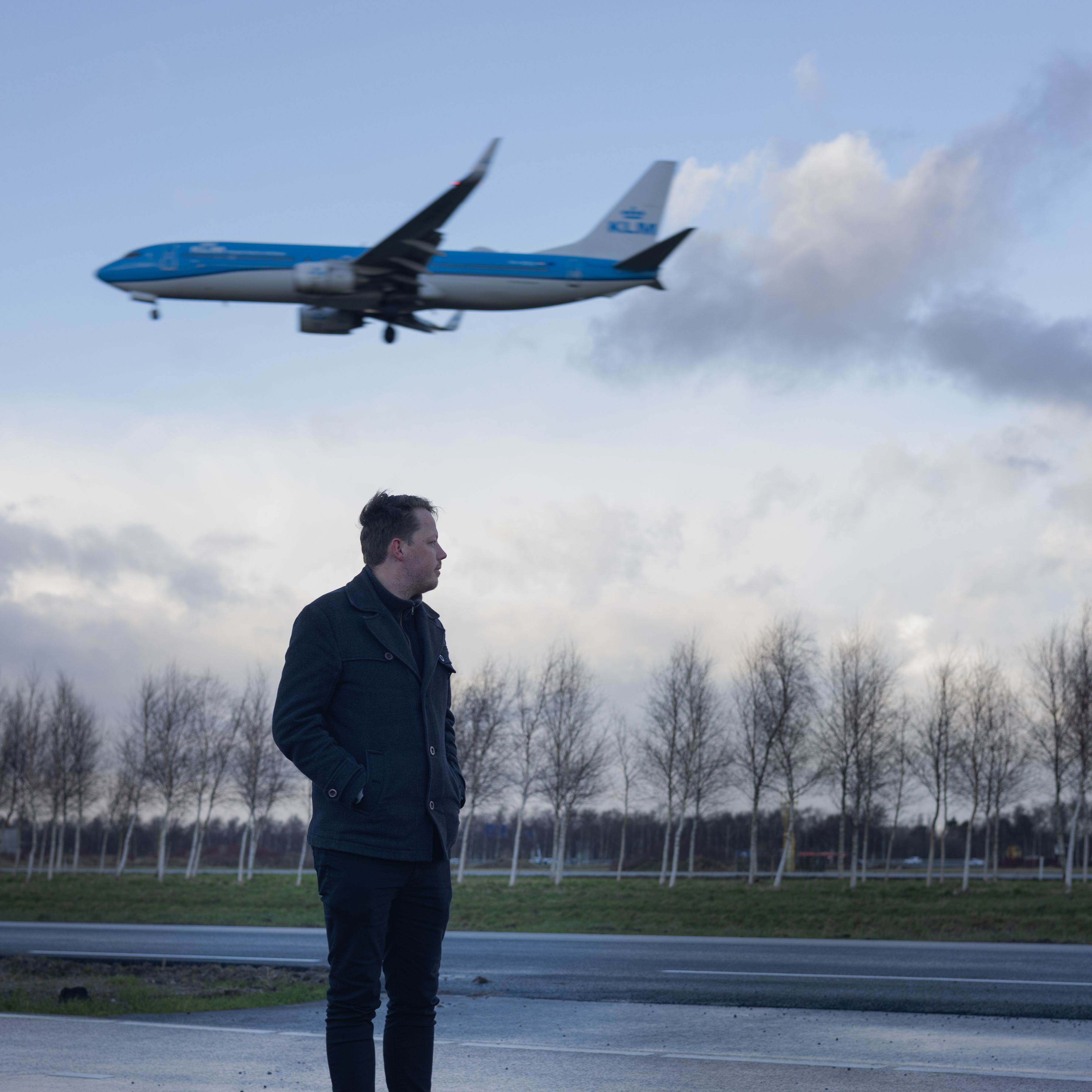 KLM-collega kijkt naar een vliegtuig dat landt.