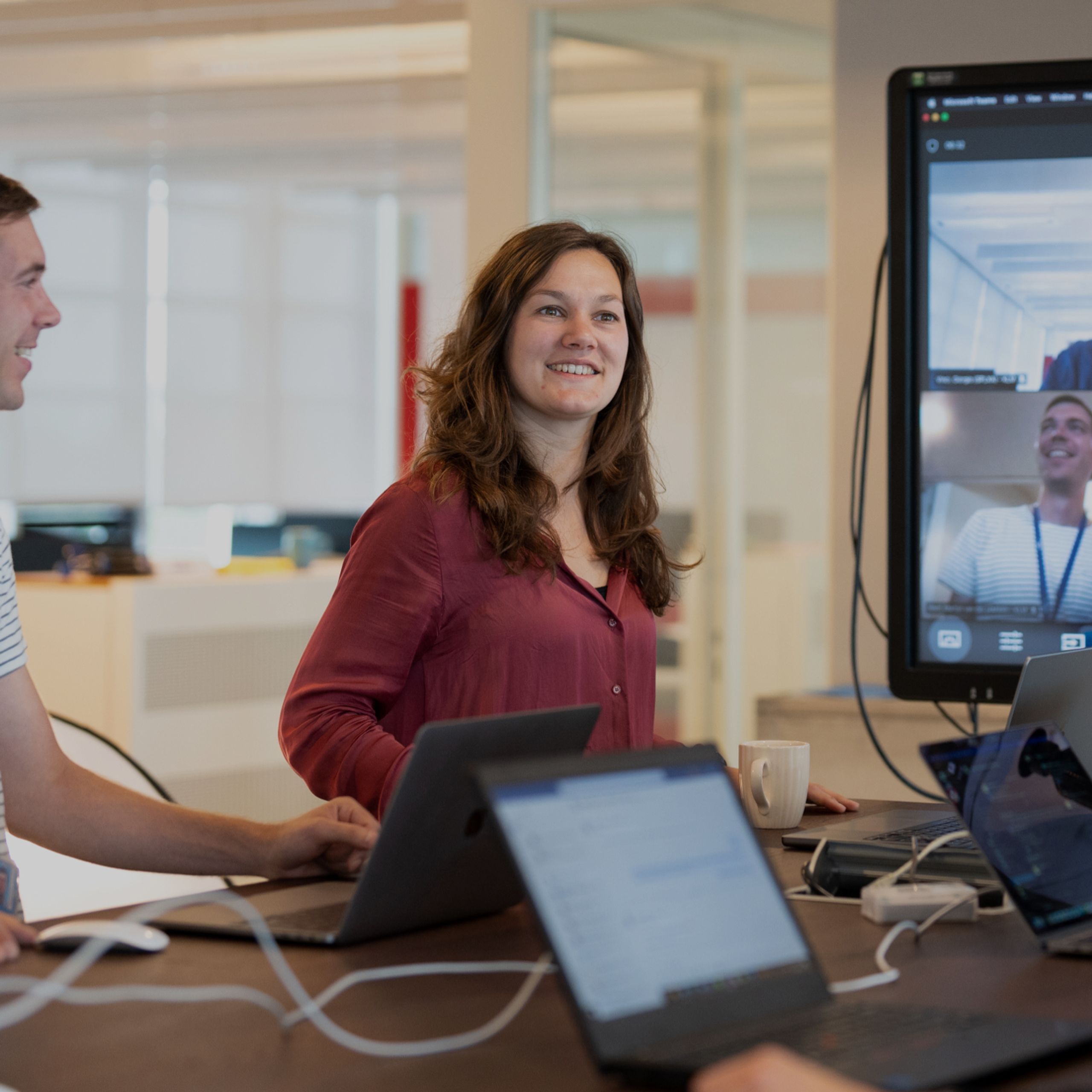 KLM-collega’s tijdens een stand-up met een Teams-vergadering op een groot scherm op de achtergrond