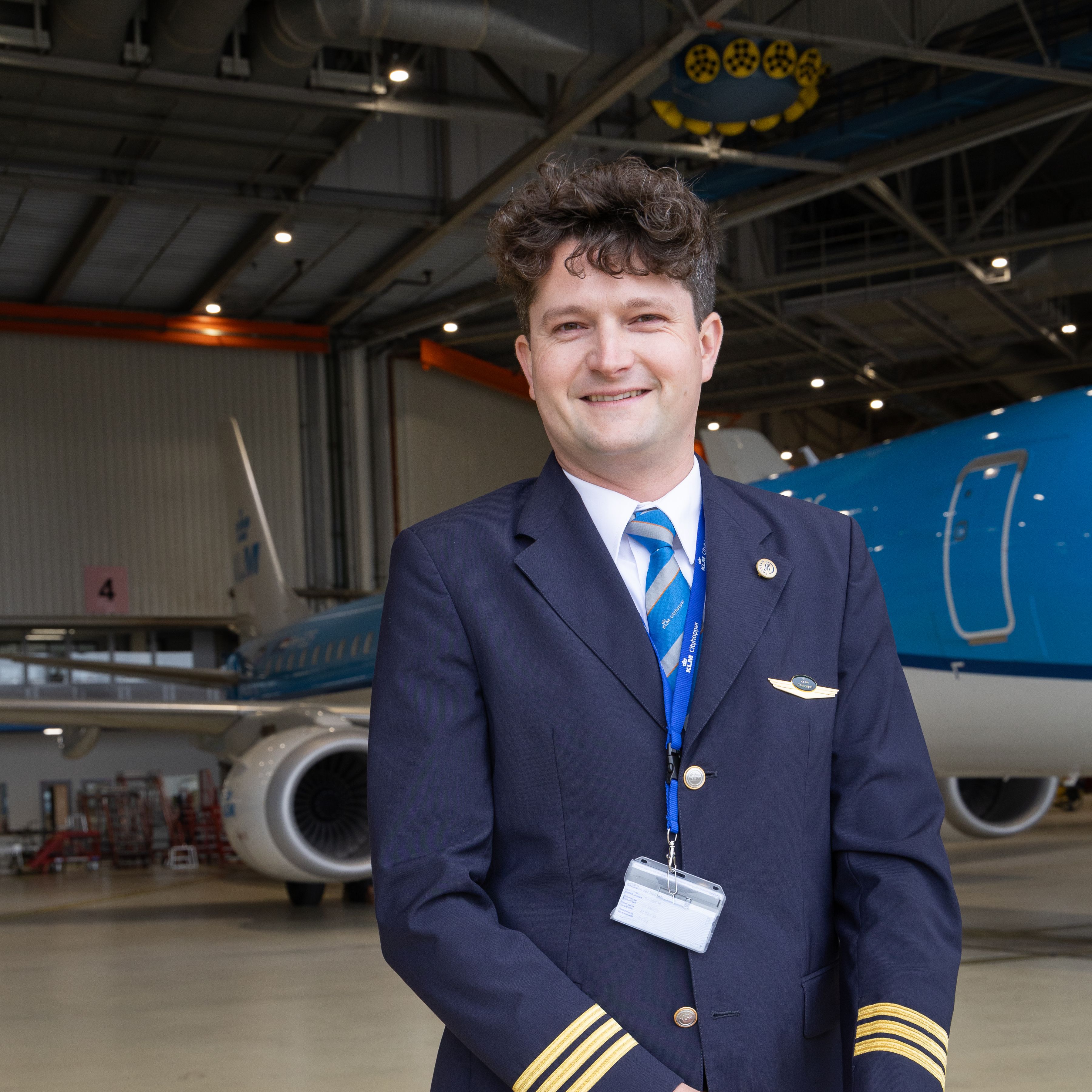 KLM Cityhopper piloot poseert in een hangaar