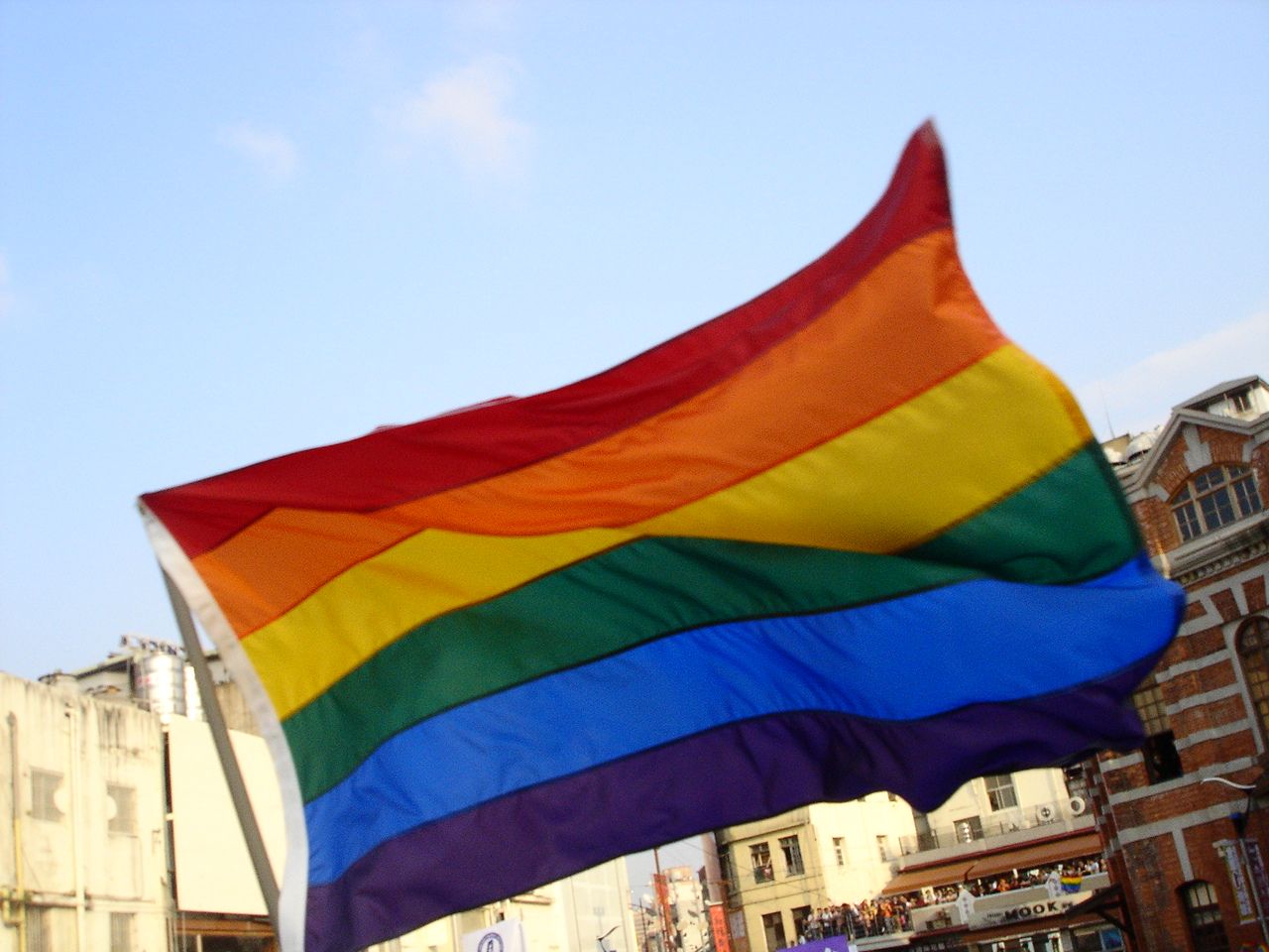 A large rainbow flag flying above the Taiwan Pride crowd in Taipei