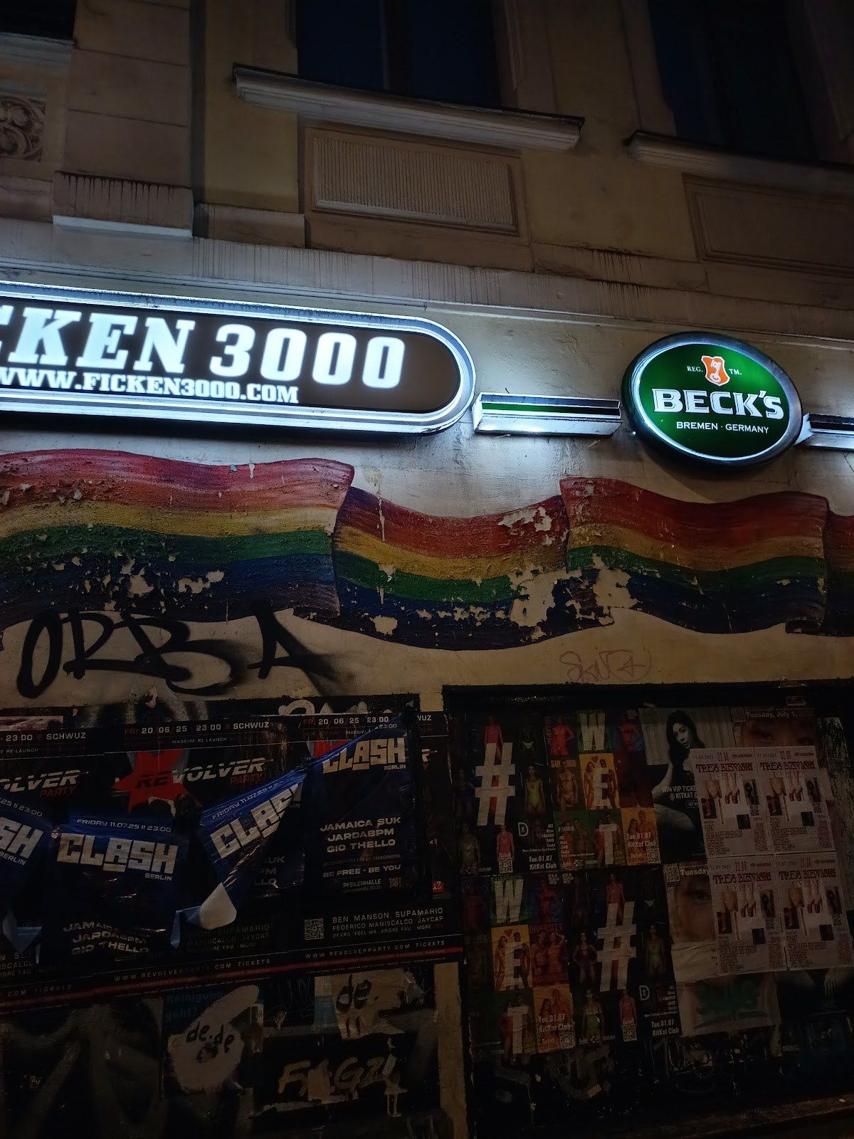 Ficken 3000 night storefront with illuminated FICKEN 3000 sign and rainbow mural