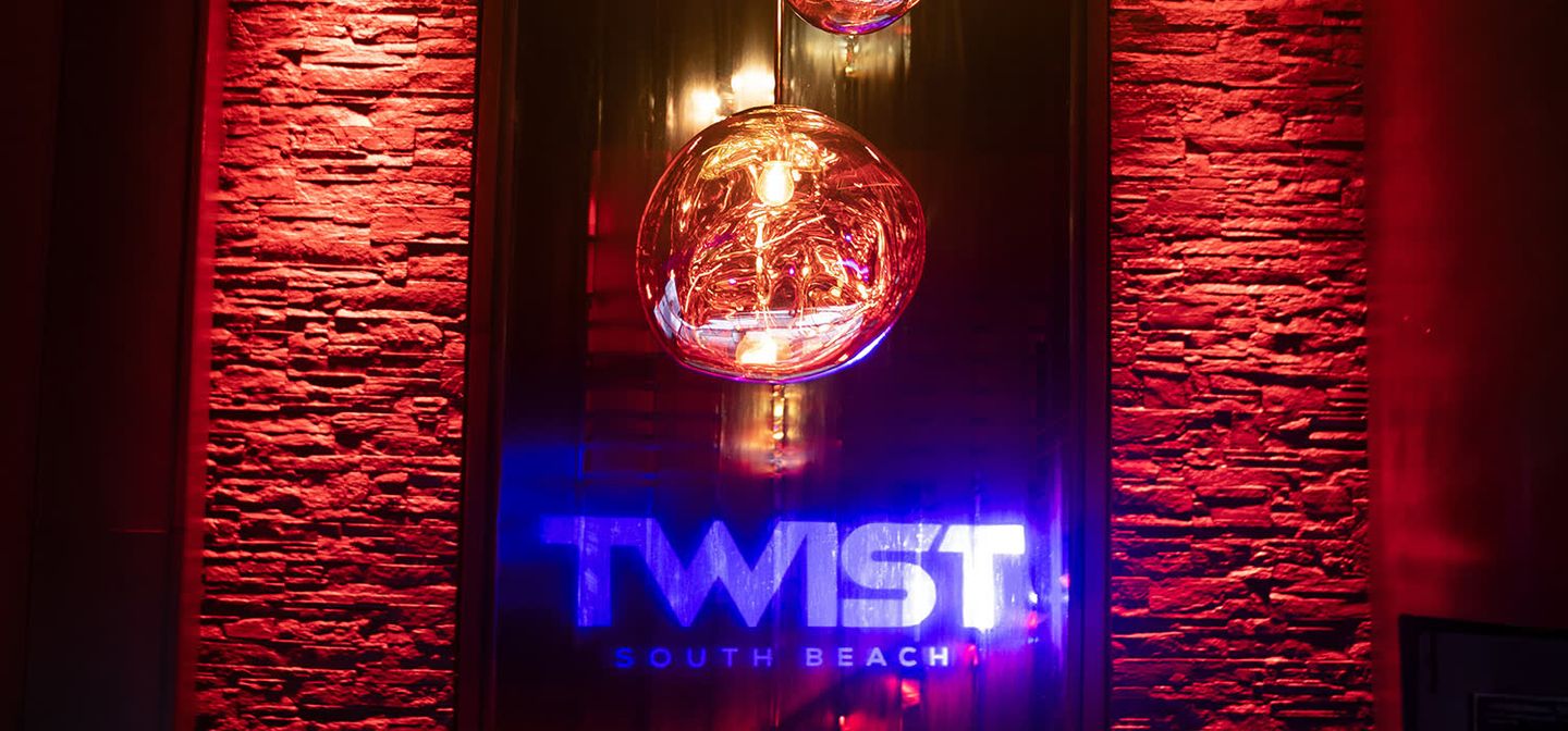 TWIST South Beach lobby neon sign reading TWIST SOUTH BEACH on a red stone wall