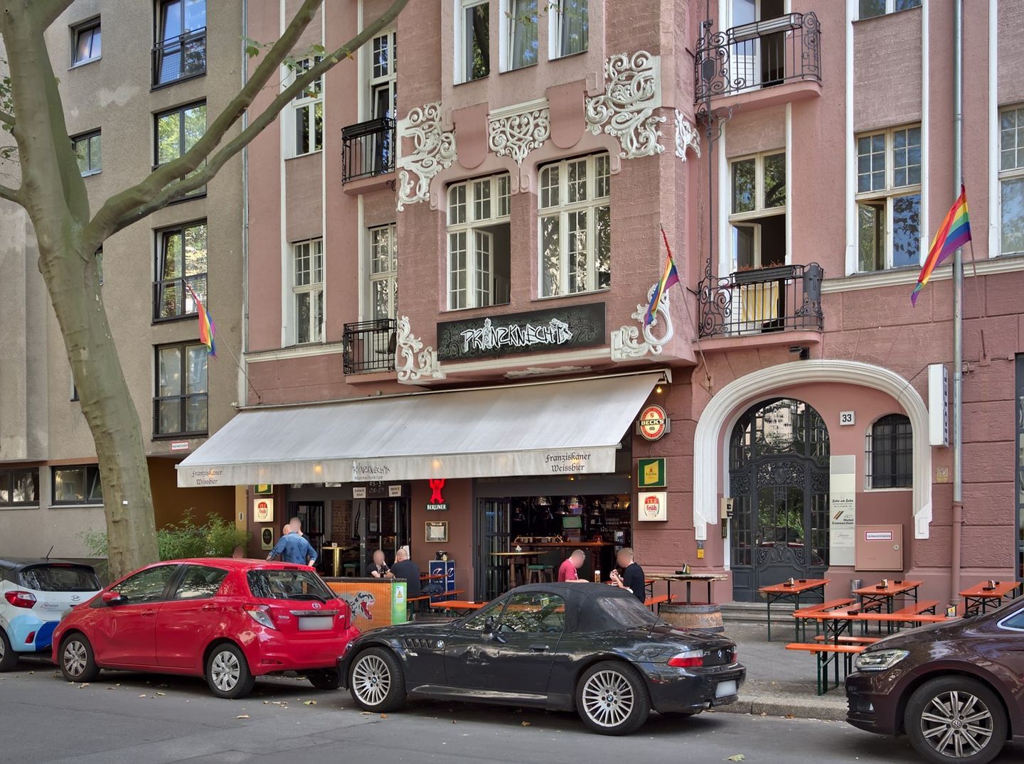 Prinzknecht storefront at Fuggerstraße 33 with outdoor seating and rainbow flags