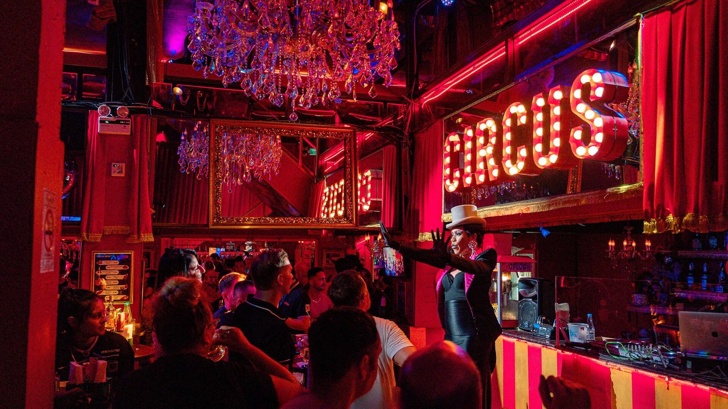 Inside Circus Soi 4: red lighting, CIRCUS marquee sign, a performer on the bar, and a packed Silom crowd