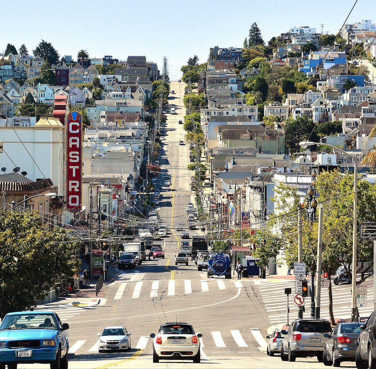 Castro Street looking into the district, with the Castro Theatre vertical sign, Market Street, and houses on the hill