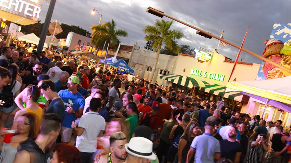 Night street crowd on Calle Ocho in front of Ball & Chain during Gay8 Festival, with festival tents