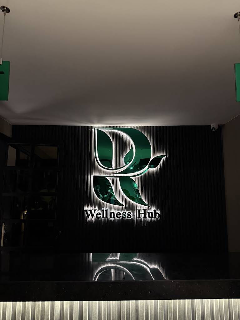 Reception wall and illuminated R Wellness Hub logo in Makati