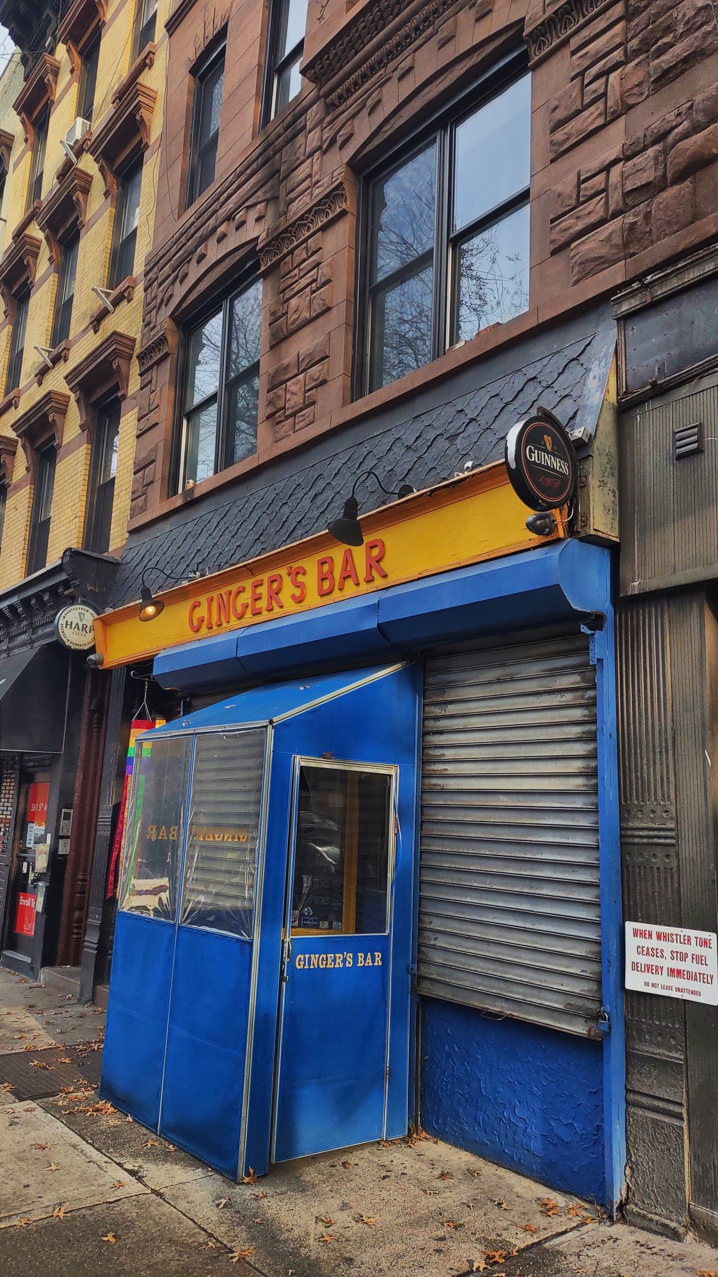 Ginger's Bar storefront on Fifth Avenue in Park Slope with the neon sign and rainbow flag