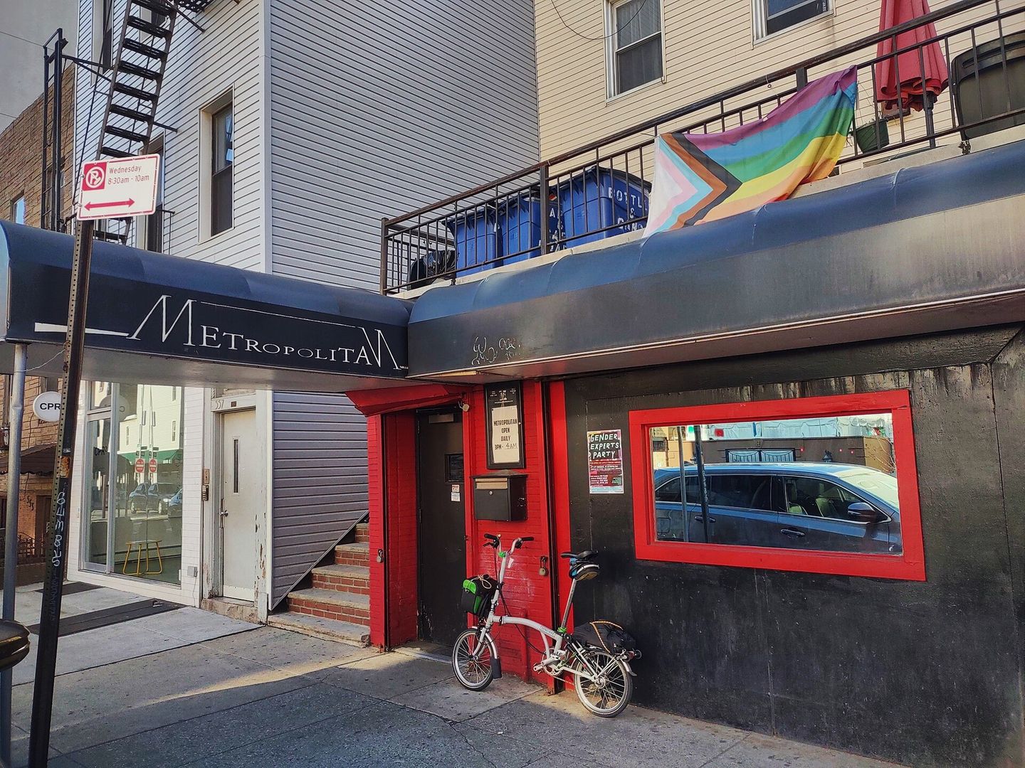 Metropolitan bar storefront with the red neon sign and rainbow flags