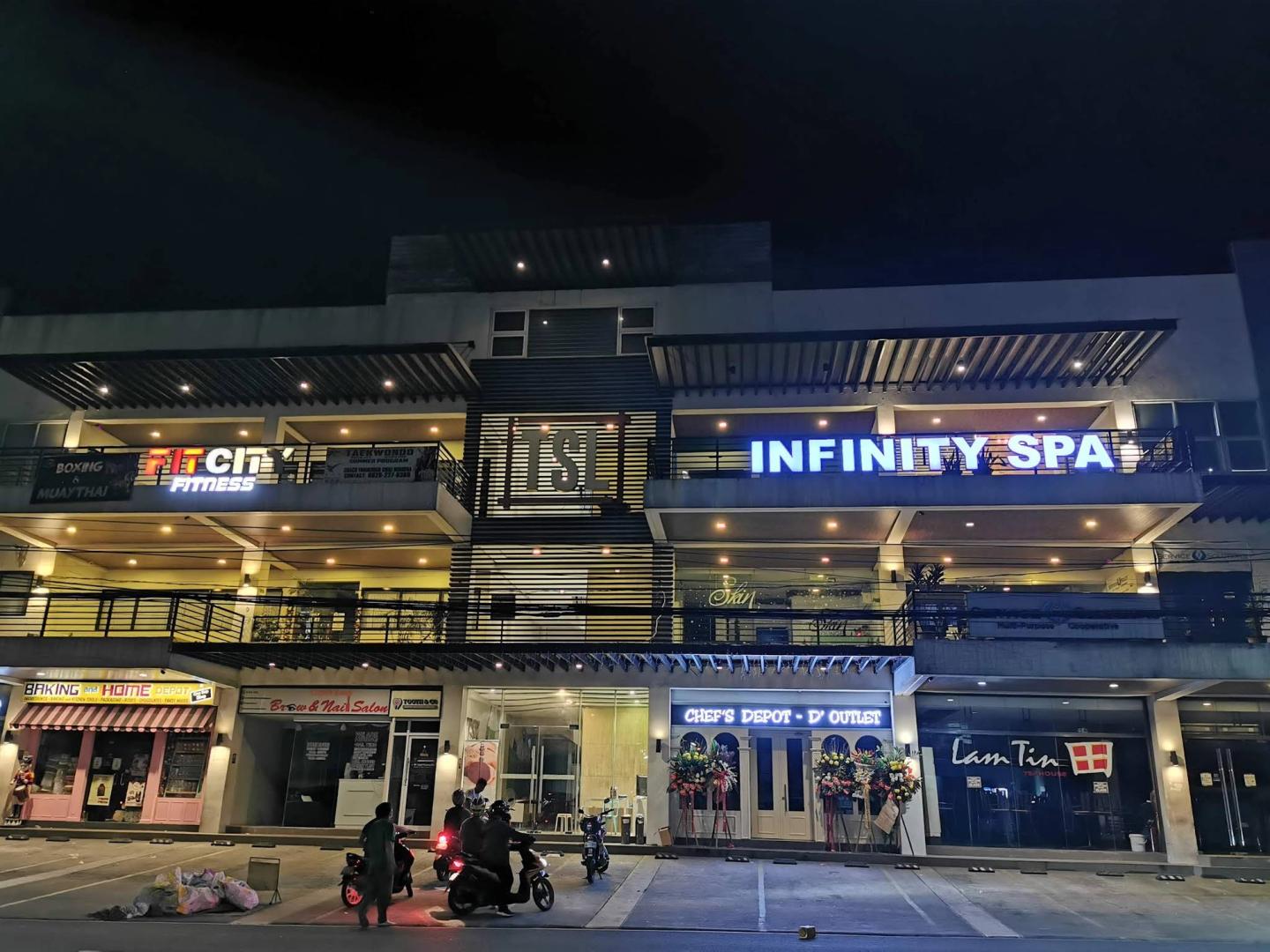 Night exterior of the TSL Building with the Infinity Spa sign in Quezon City