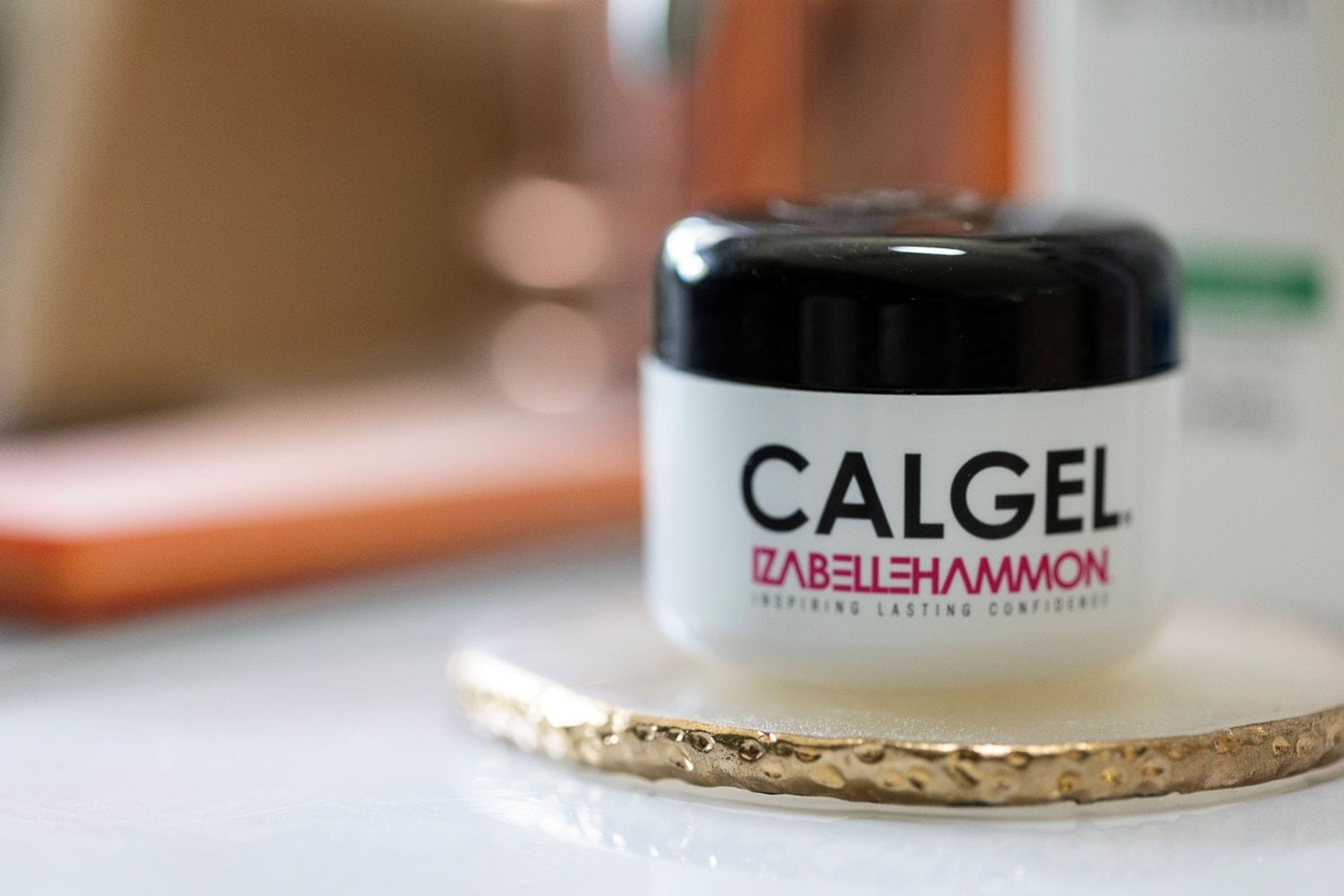 Pot de Calgel® Izabelle Hammon posé sur un sous-verre doré, en gros plan.