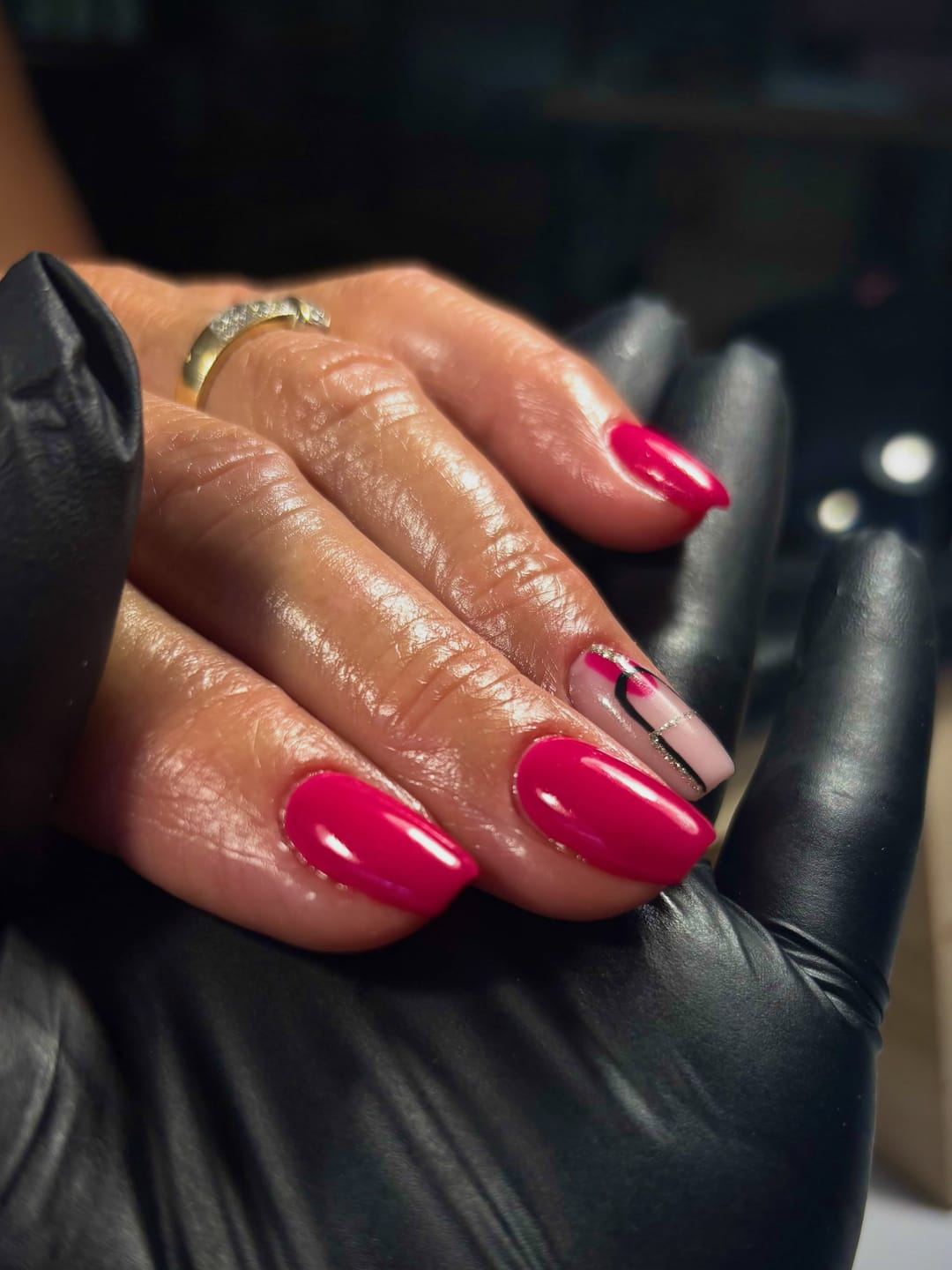 Main aux ongles fuchsia brillants, posée sur un cuir noir.