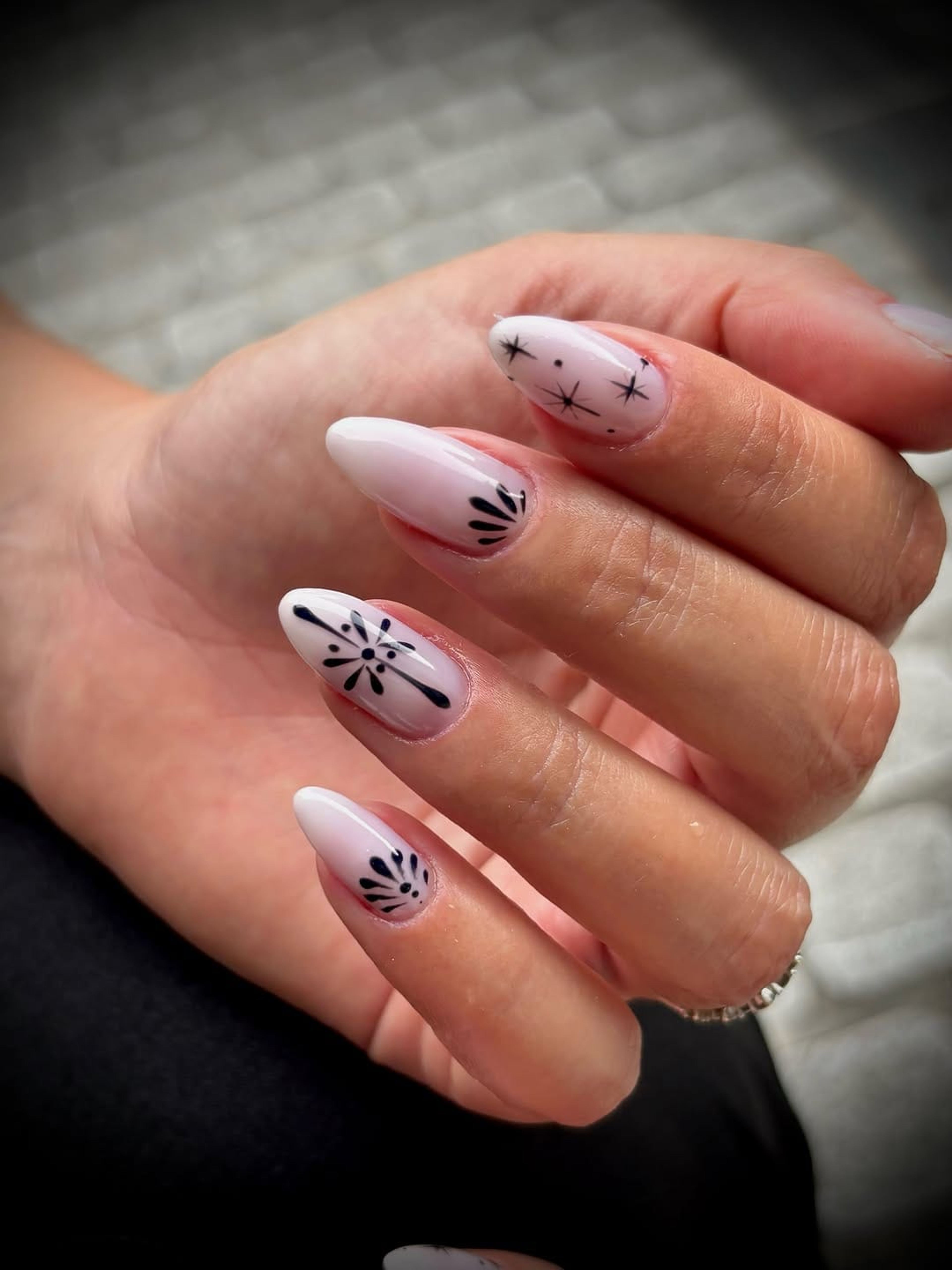 Ongles amande blancs ornés d’éventails noirs dessinés à la main.