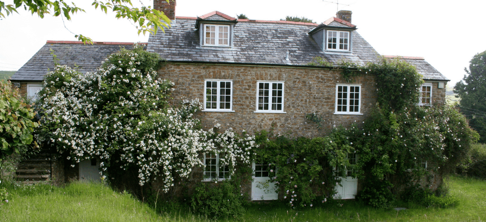Home stewardship country house with climbing roses and mature garden planting