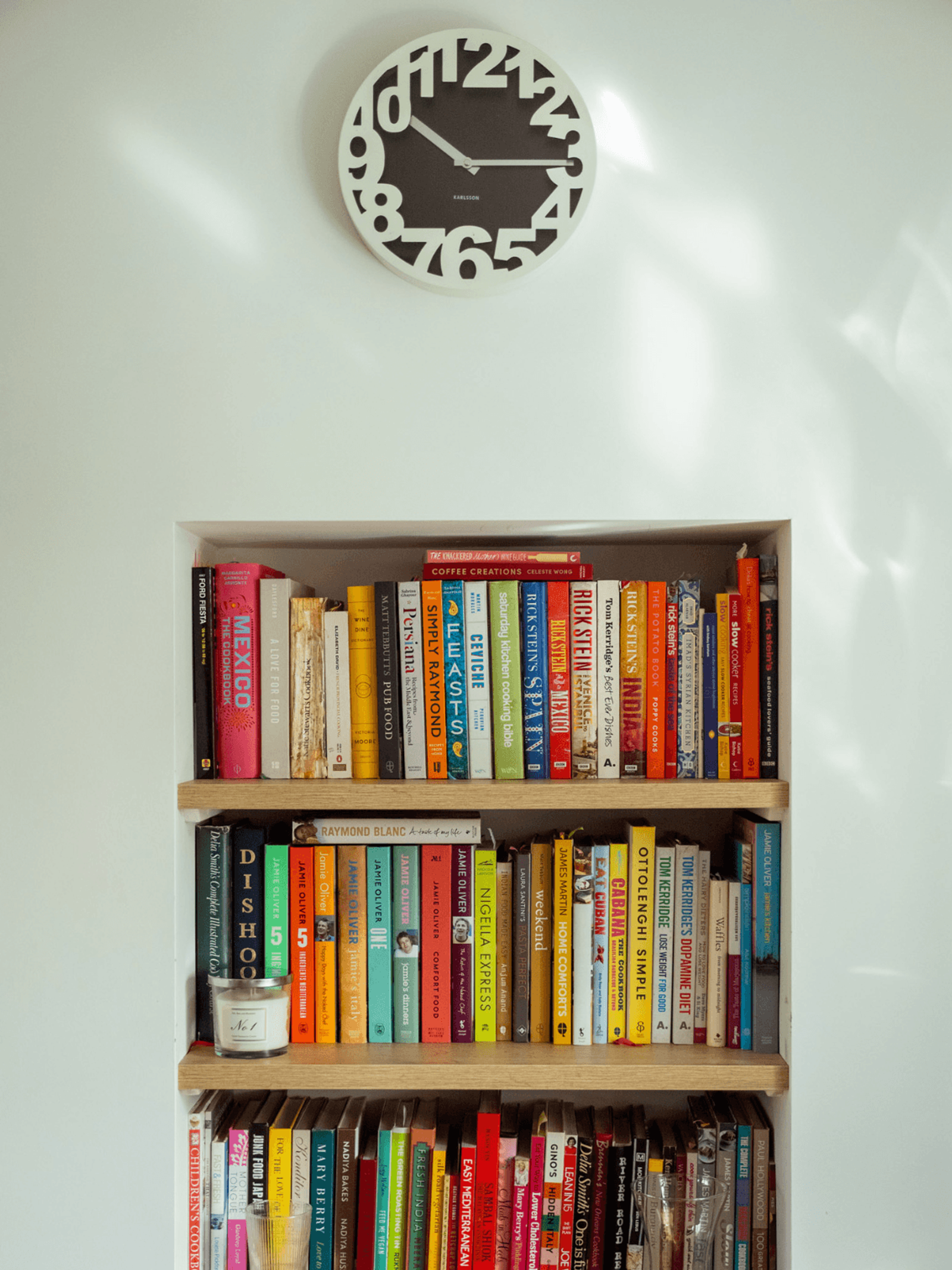 Kent home interiors cookbook shelf with colourful recipe books and modern wall clock