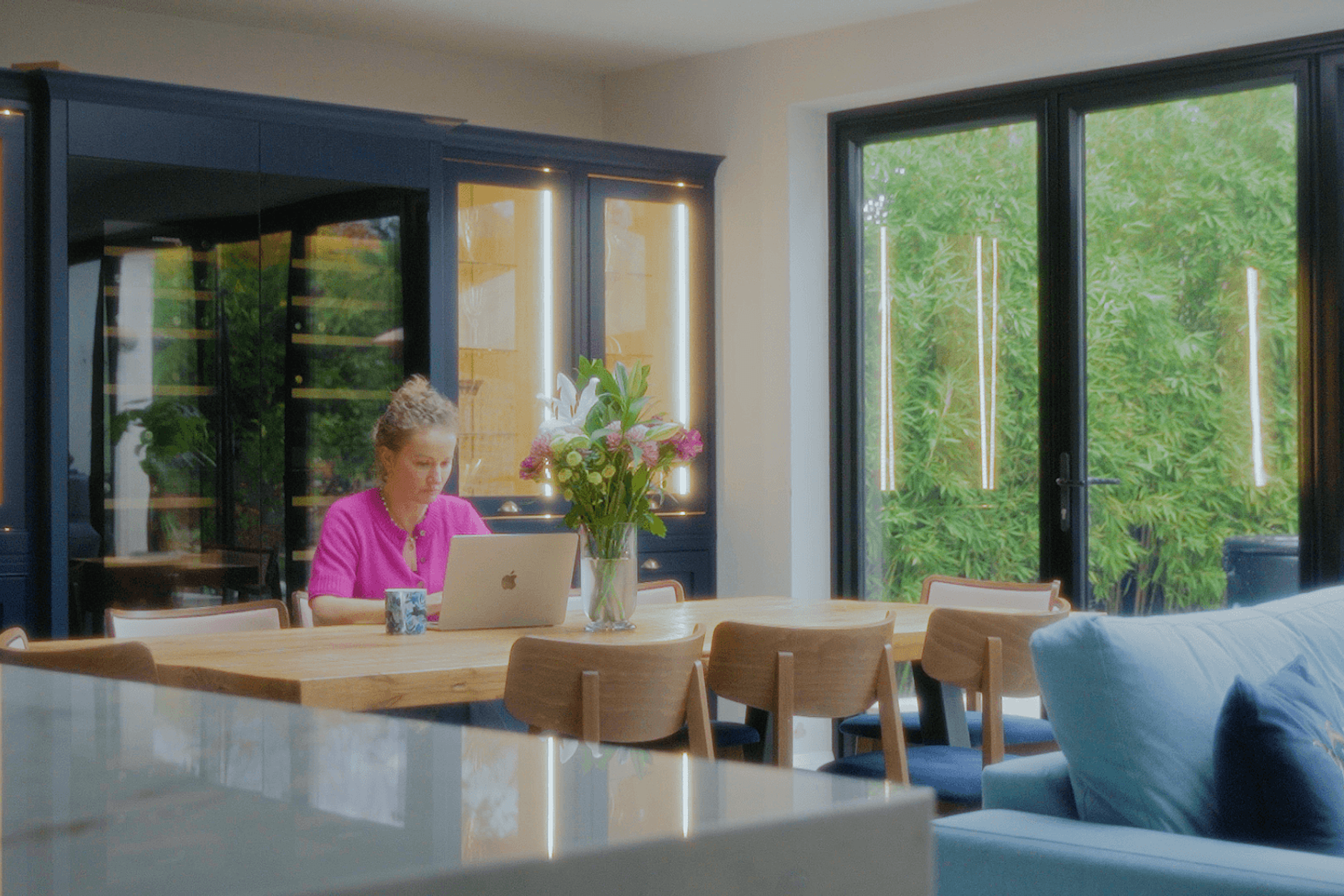 Beckenham home interiors dining area with timber table, built-in blue cabinetry and garden view