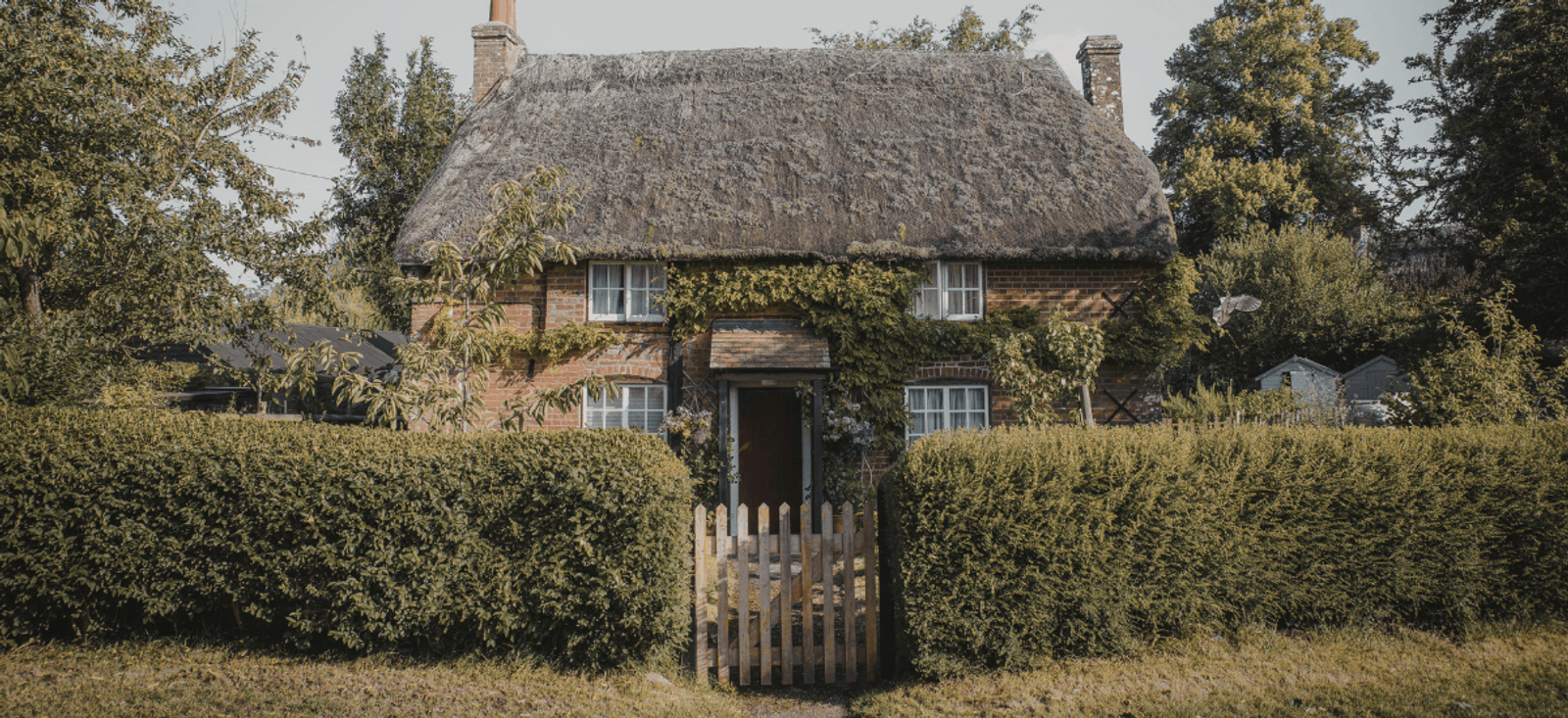 Home stewardship example with well-maintained cottage, tidy hedging and cared-for garden