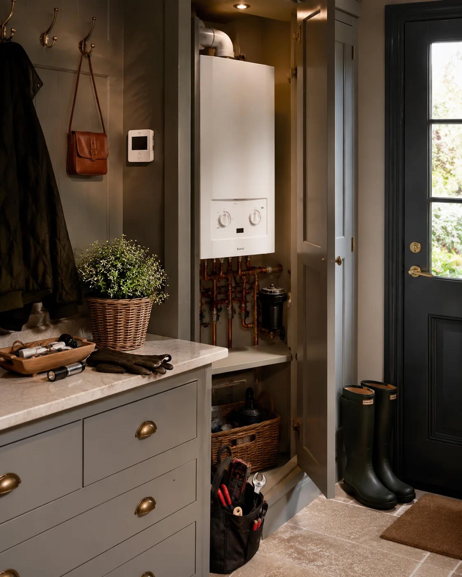 A boot room with a wall-mounted boiler and thermostat, ready for an autumn heating check.
