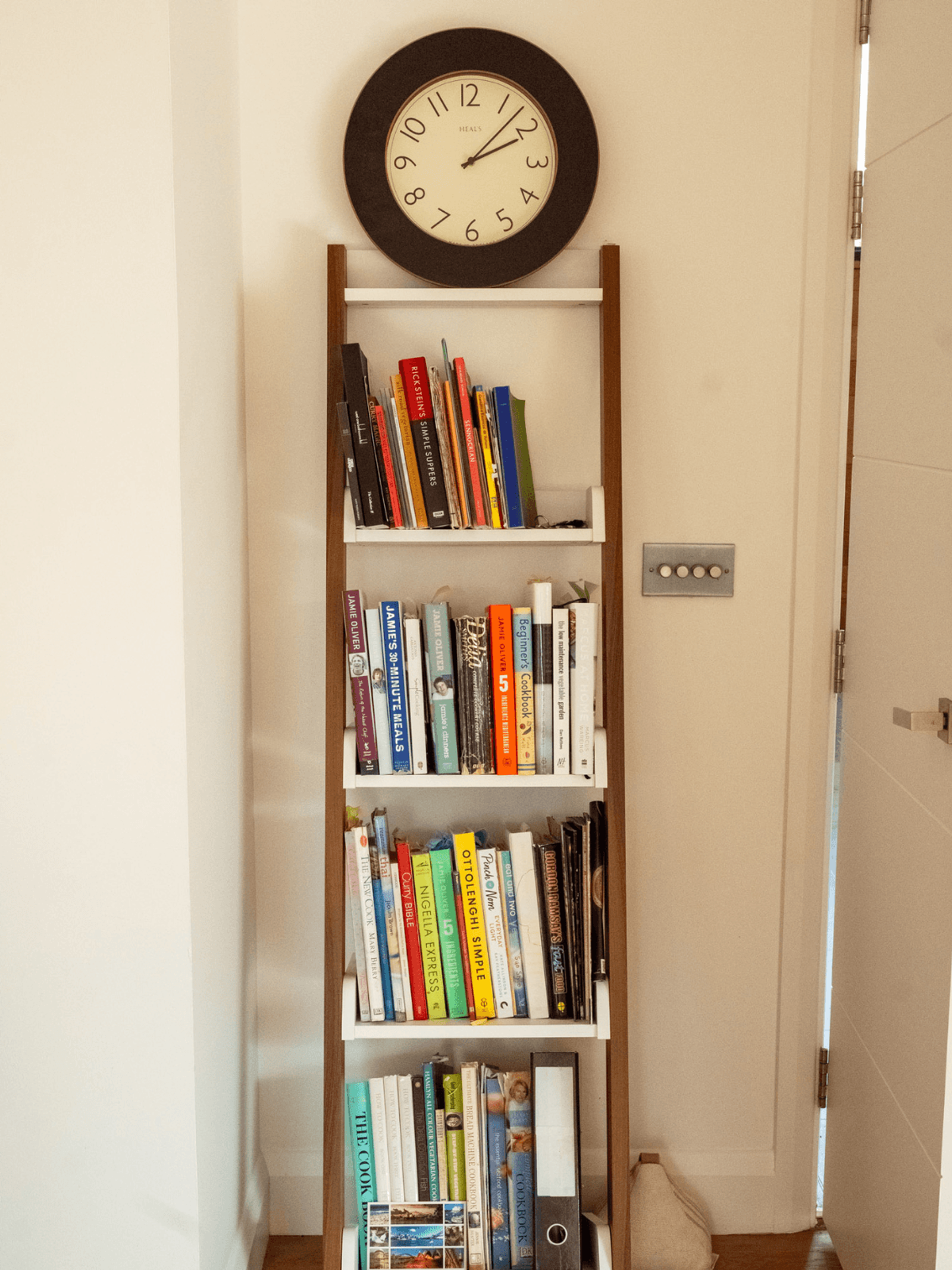 Sevenoaks interior design with ladder bookshelf displaying cookbooks and wall clock
