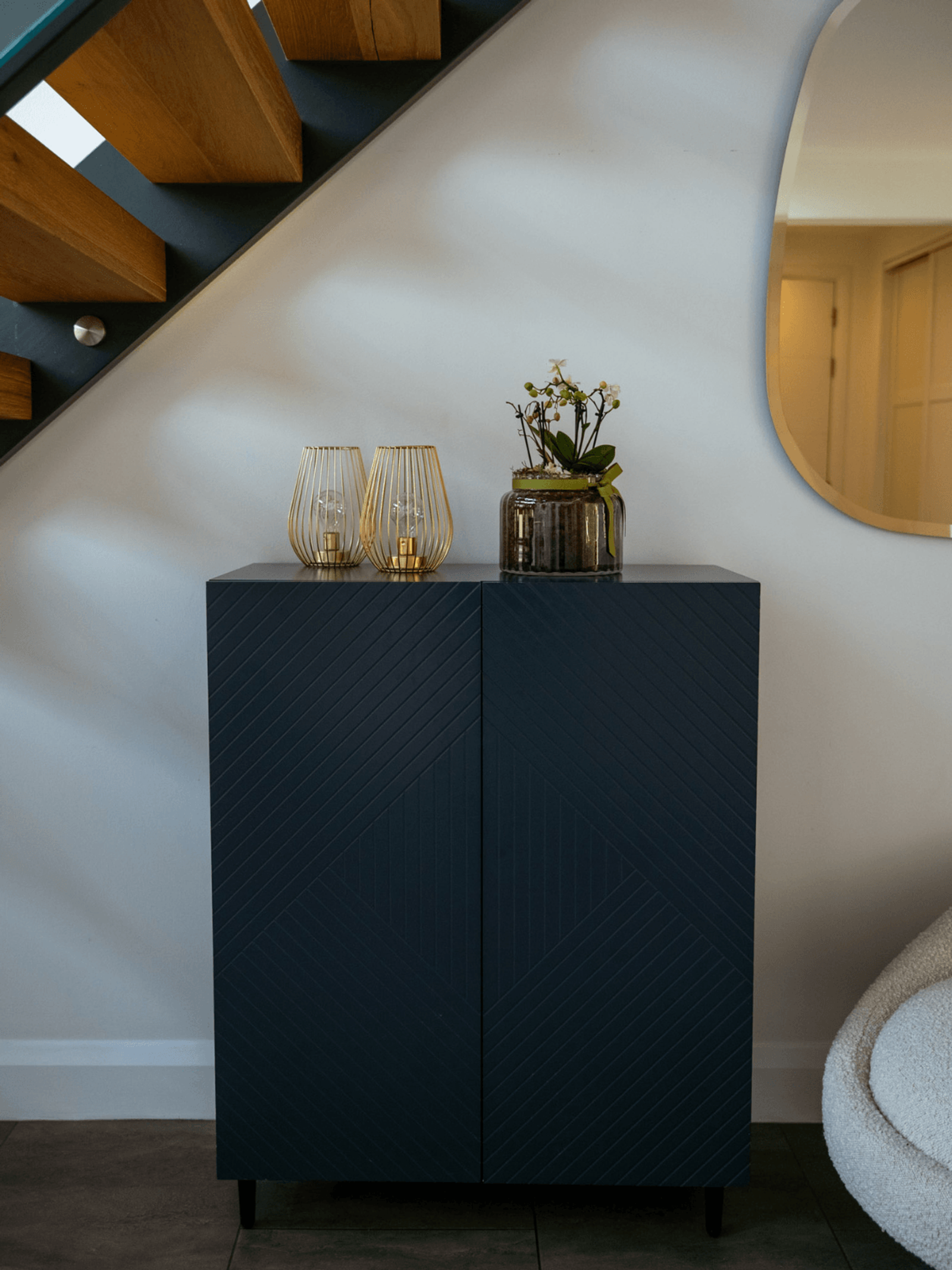 Sevenoaks interior design hallway with dark cabinet, decorative lighting and orchid styling beneath staircase