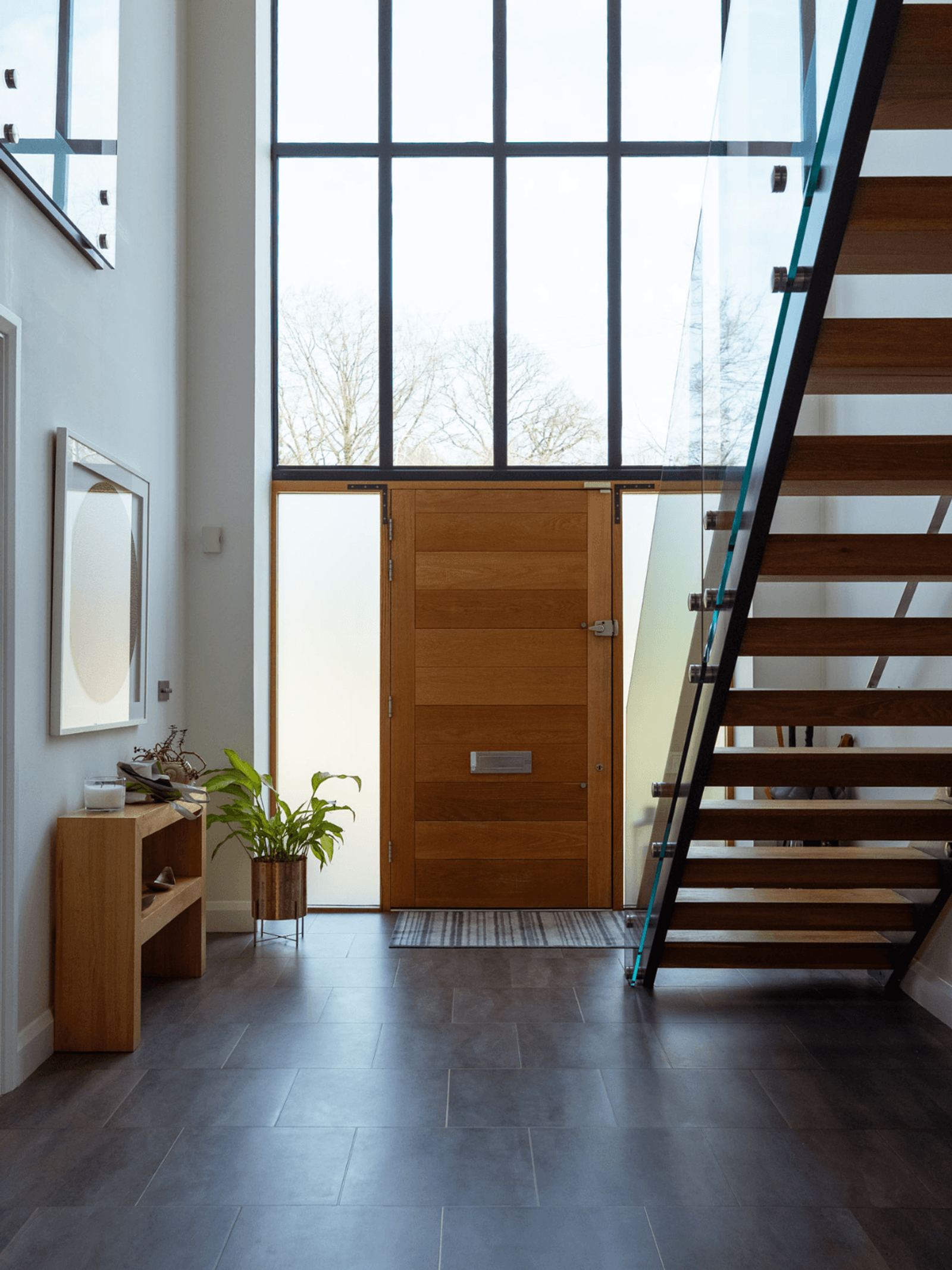 Sevenoaks interior design modern hallway with timber front door, large window and glass staircase