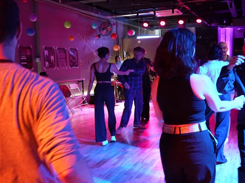 Couples fill the floor at a Big Apple Ballroom event night, the live band playing behind the red rope.