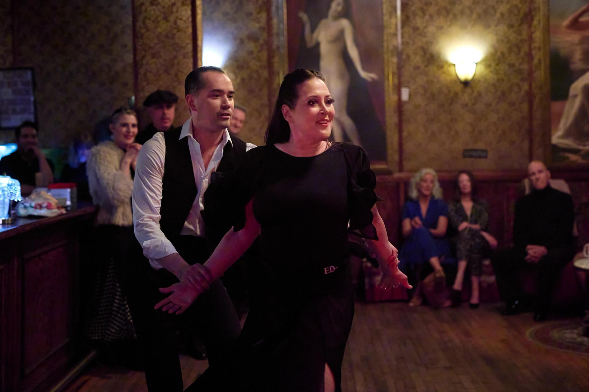 A couple in black stepping in sync through a hustle at the NY Nightlife Showcase.