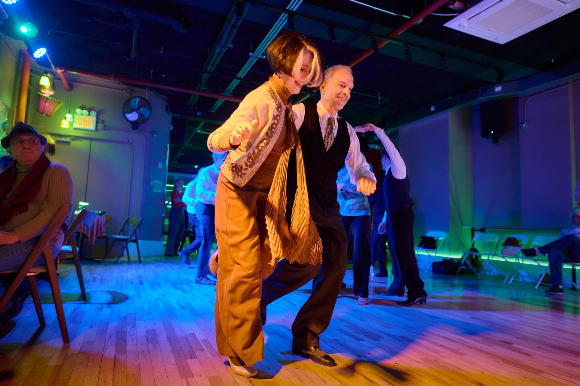 A couple in vintage dress trotting side by side across the floor at a Big Apple Ballroom Salon Series night.