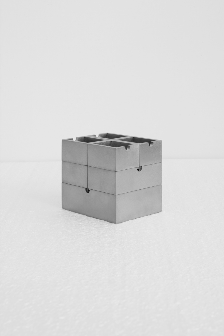 Placeholder reference image: Small geometric metal block with visible seams and recessed top details.