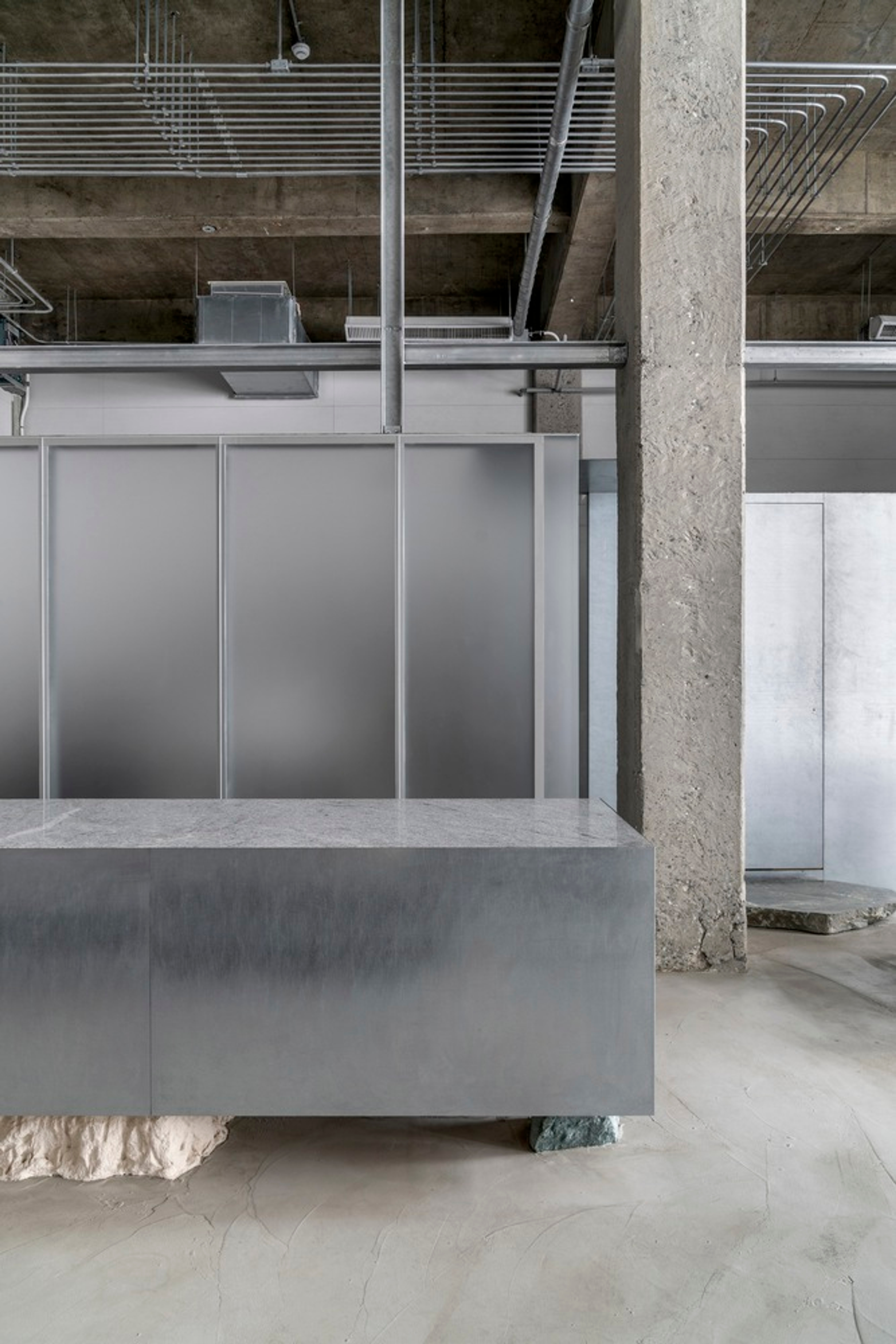 Placeholder reference image: Metal counter, glass partition and structural column in a concrete interior.