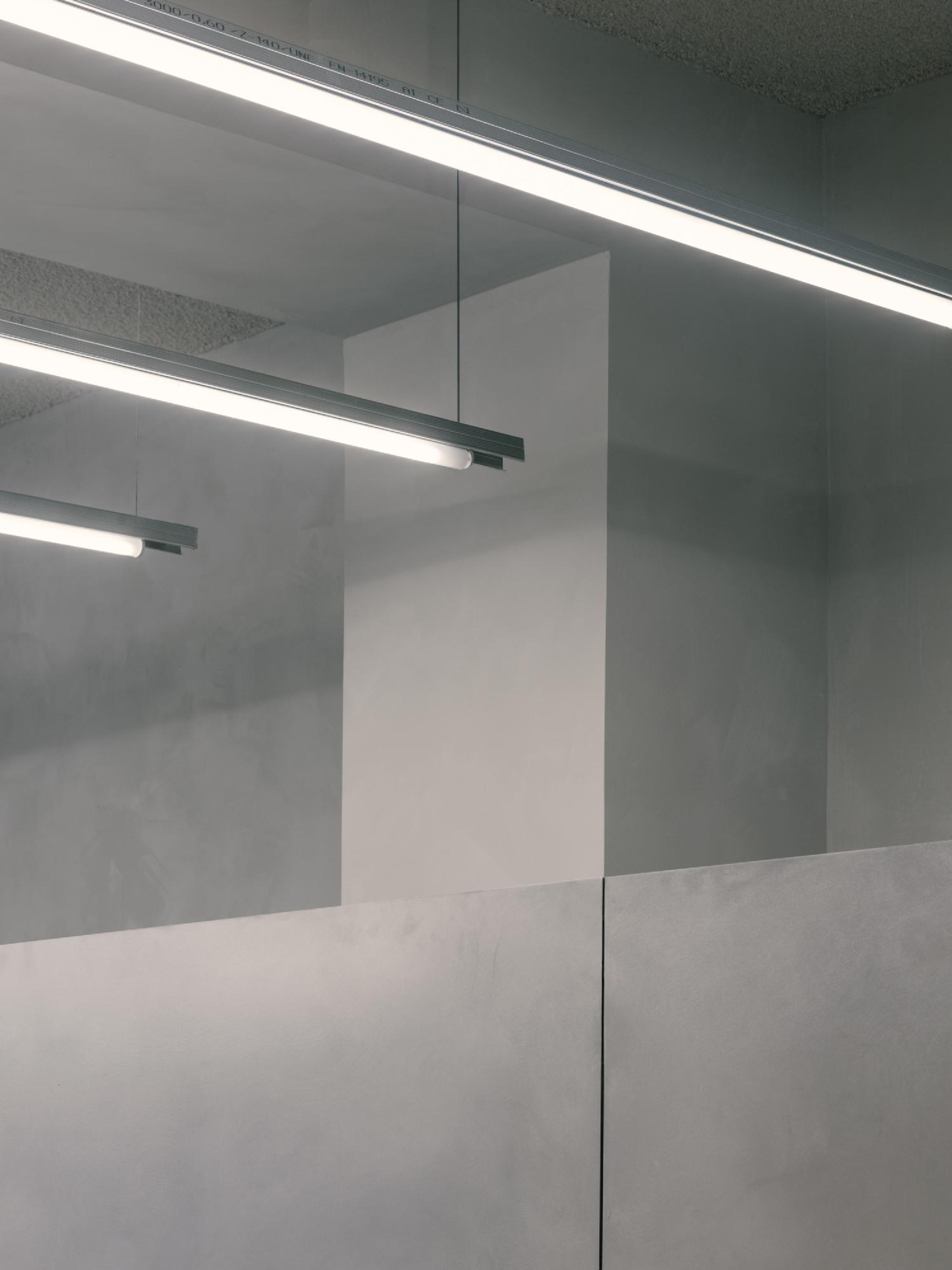 Placeholder reference image: Suspended linear lighting above pale partitions in a concrete interior.