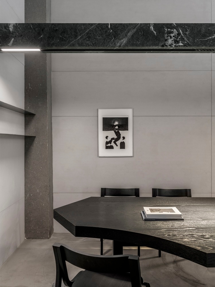 Placeholder reference image: Dark timber dining table and chairs within a pale concrete and stone interior.