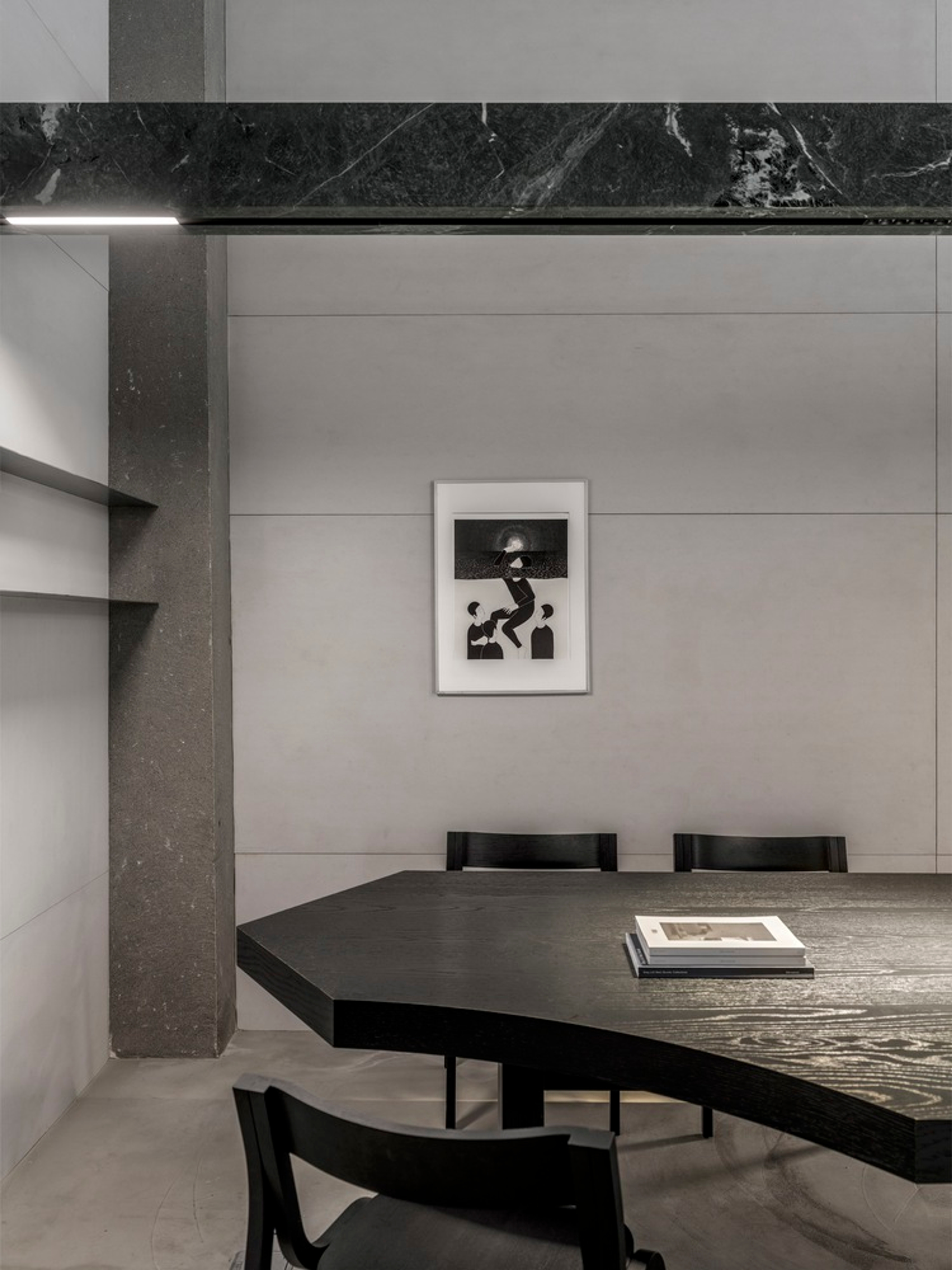 Placeholder reference image: Dark timber dining table and chairs within a pale concrete and stone interior.