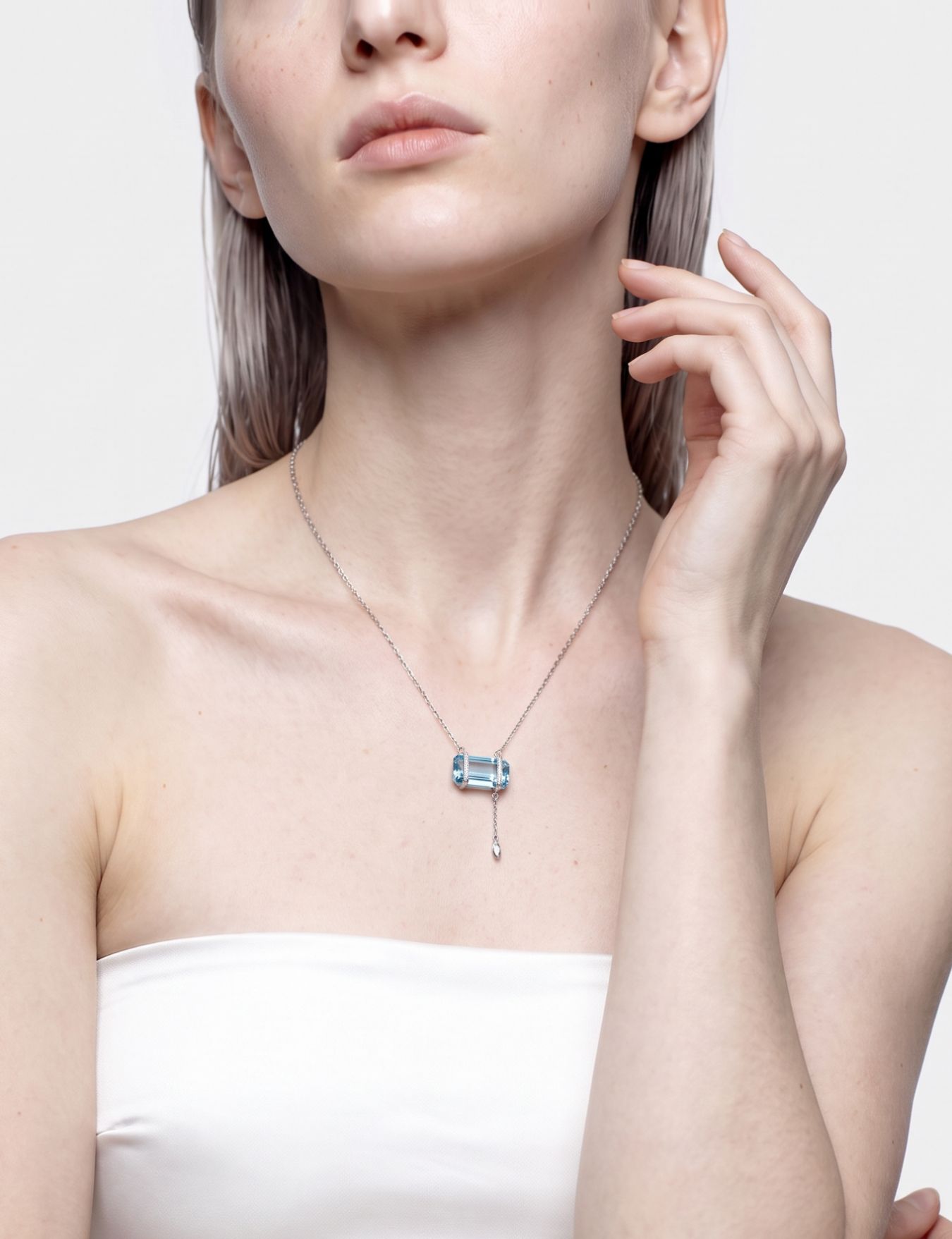 Model wearing the Horizon aquamarine bar pendant necklace, hand raised to the chin