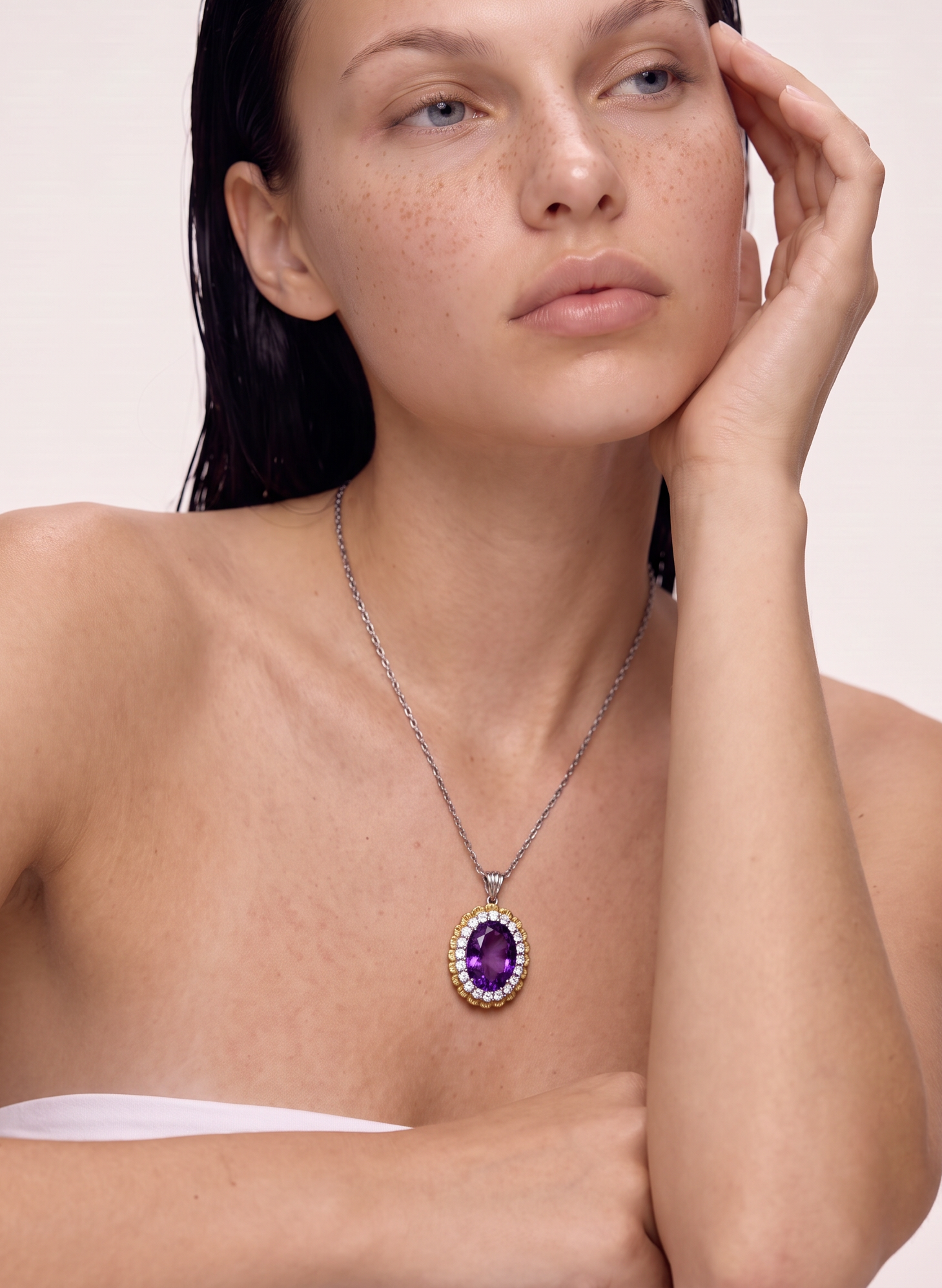 Model wearing the Royal Tide amethyst halo pendant necklace, hand raised to the face